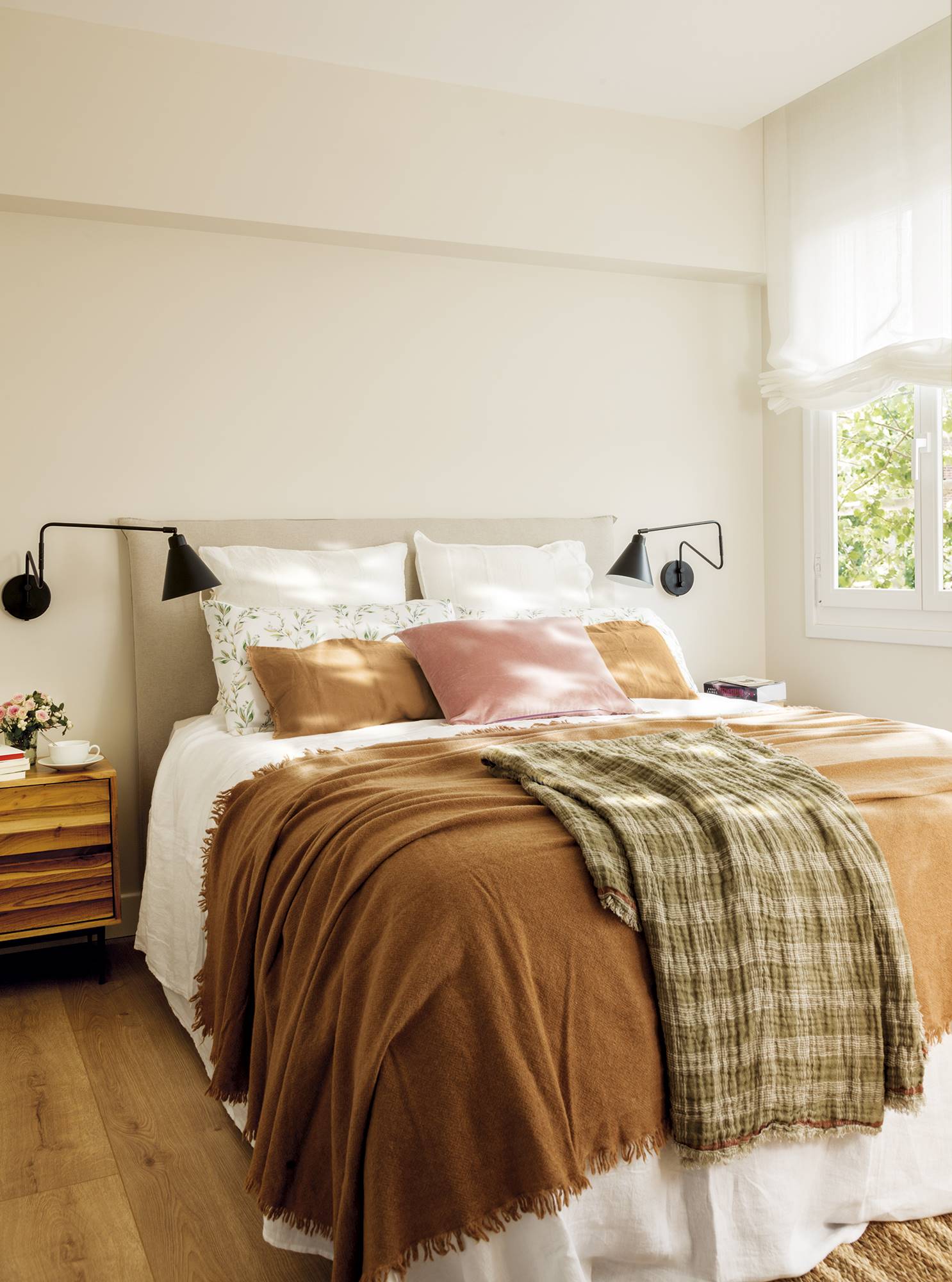 Dormitorio con textiles color tierra y cabecero tapizado. 