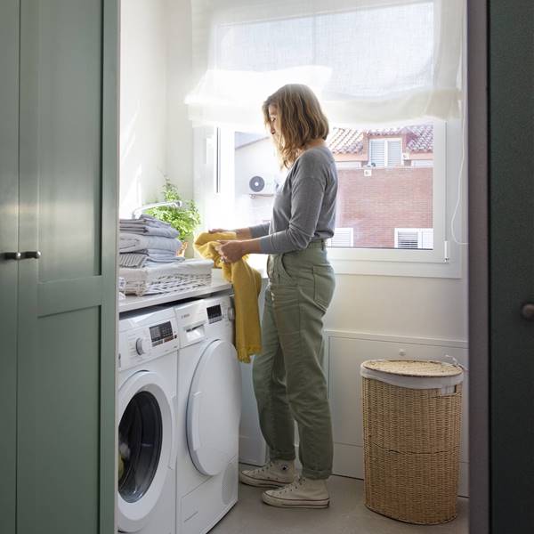 mujer recogiendo ropa de la colada junto a una lavadora 00532170 O