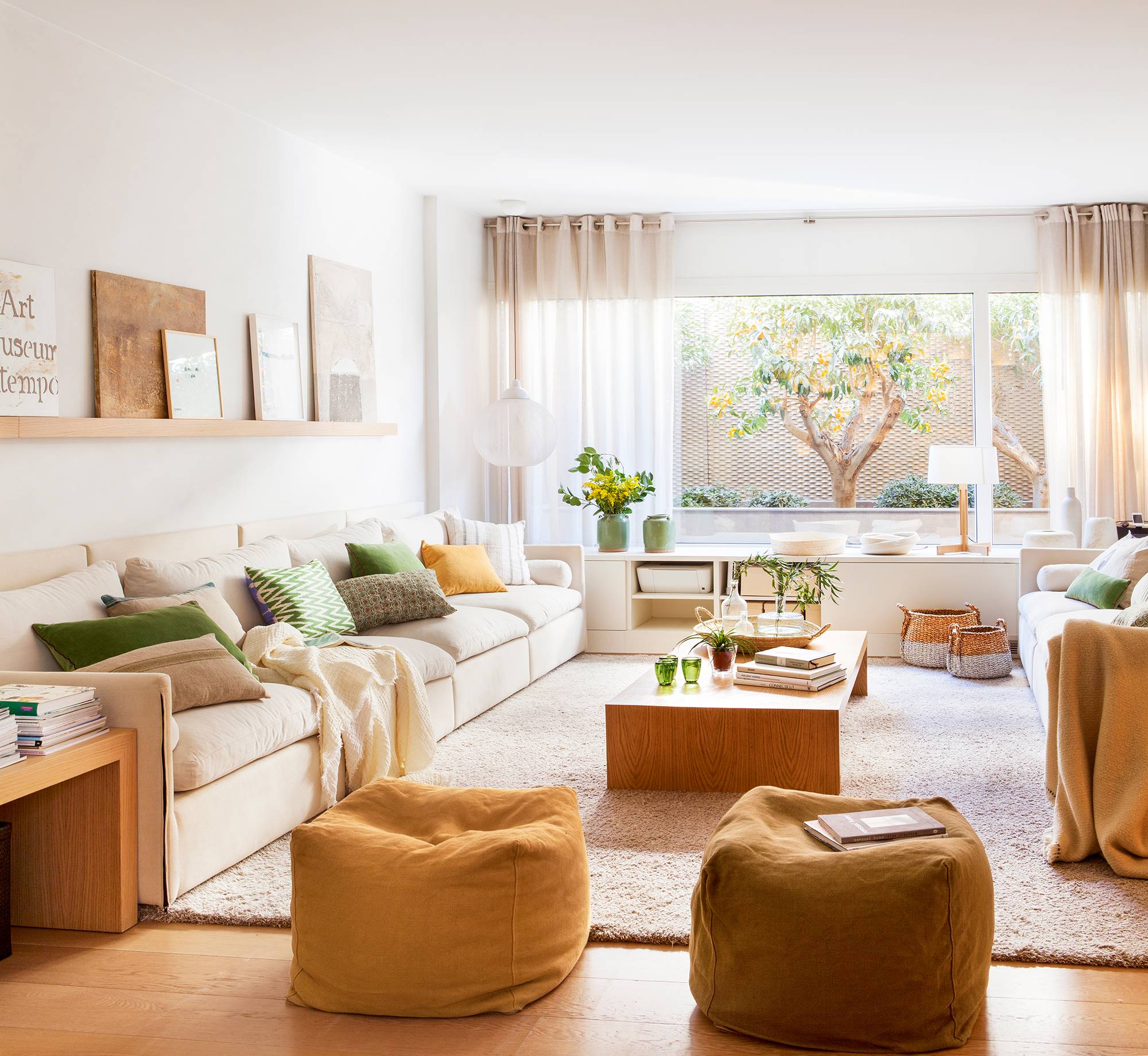 Salón con sofás blancos, alfombra de pelo, mesa de centro de madera y puffs de terciopelo en colores ocre 00426437