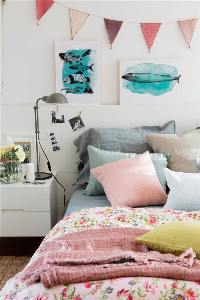Habitación juvenil con cuadros azules, ropa de cama de flores y banderines de colores
