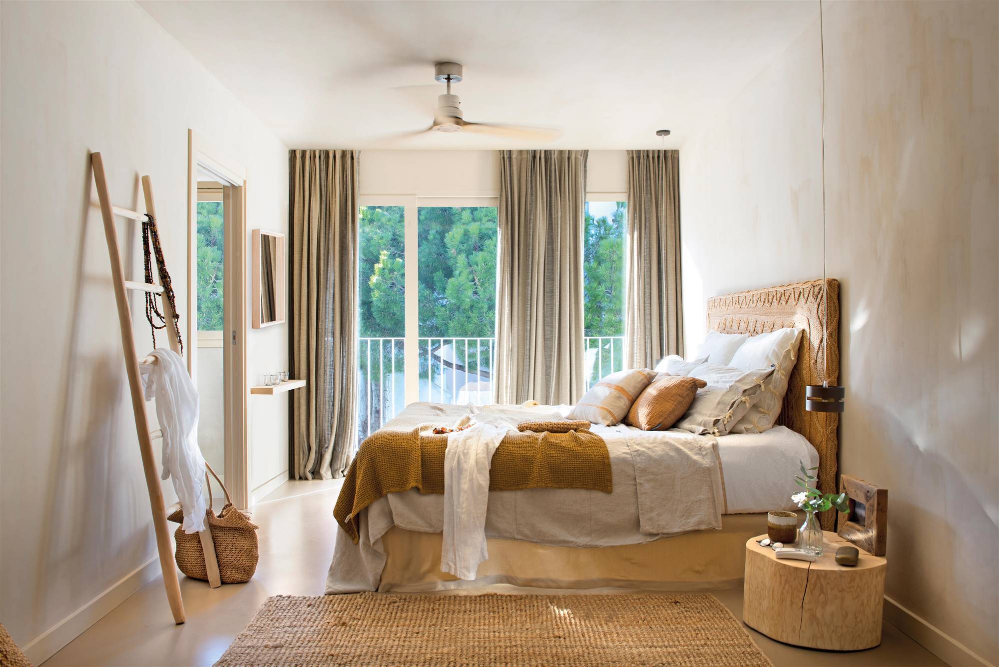 Dormitorio boho chis con cabecero y alfombra de fibra natural. 