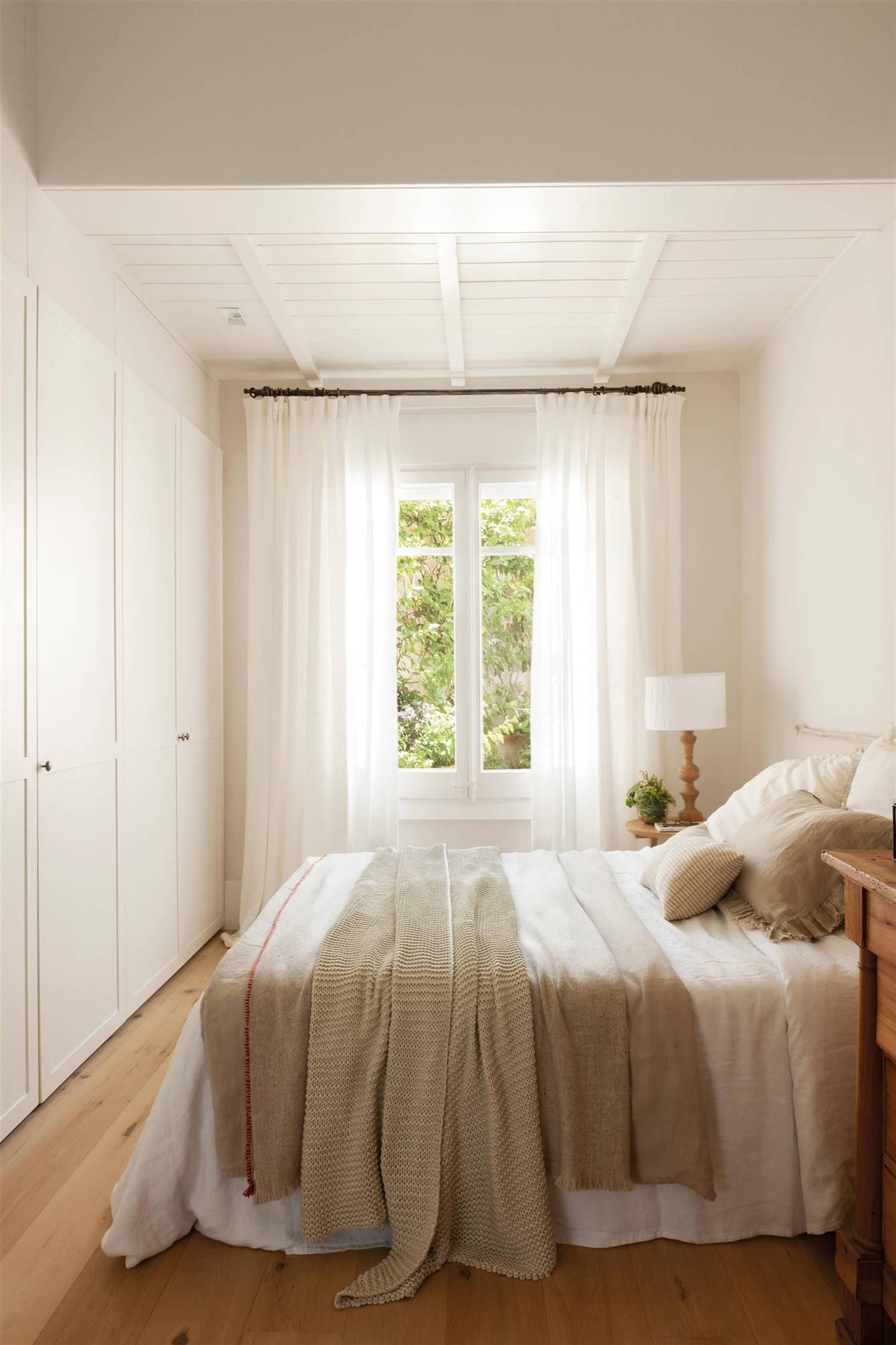 Dormitorio minimalista con armarios empotrados y ropa de cama blanca. 