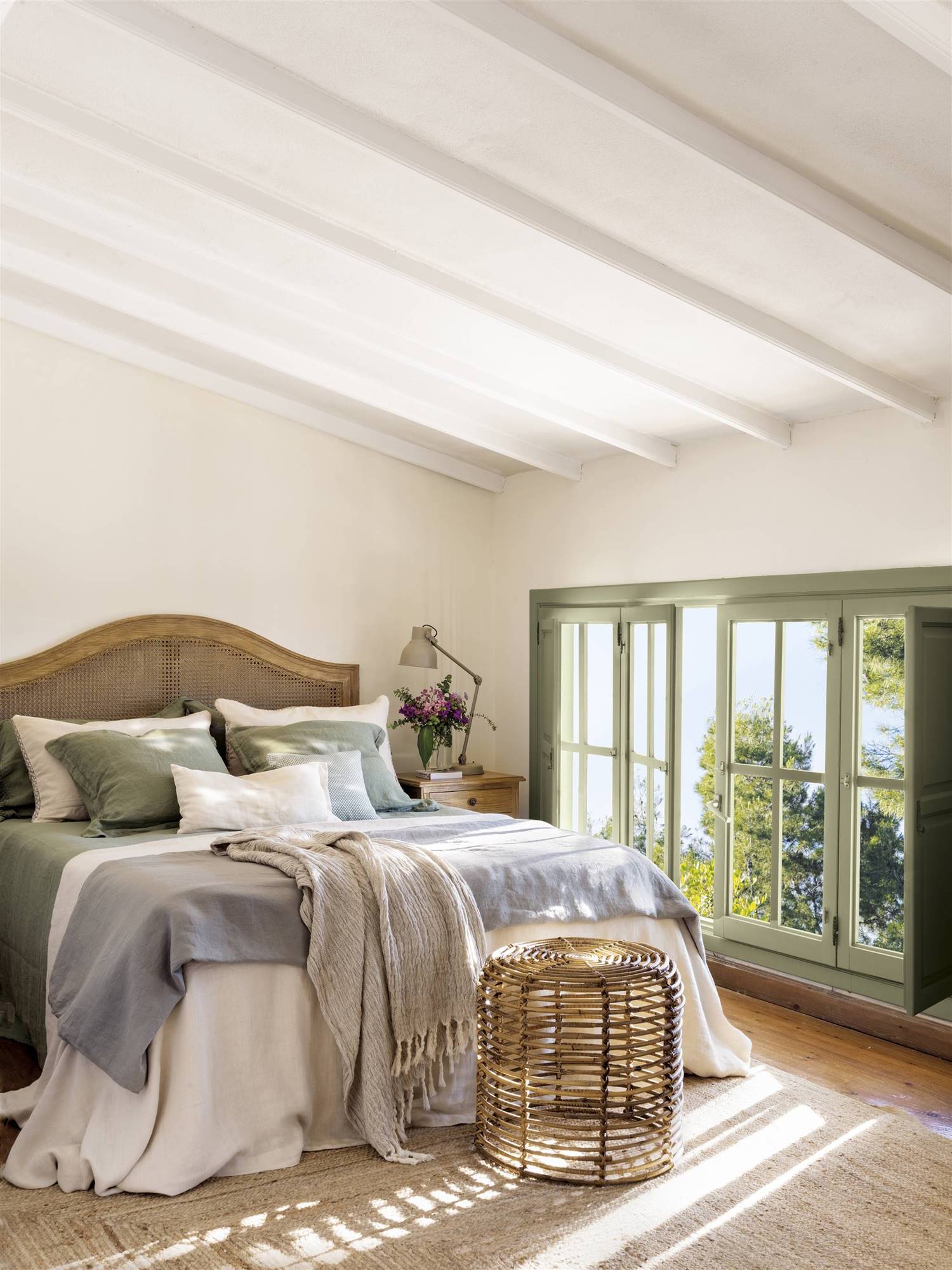Dormitorio clásico con cabecero tapizado de madera y ropa de cama blanca, azul y verde.