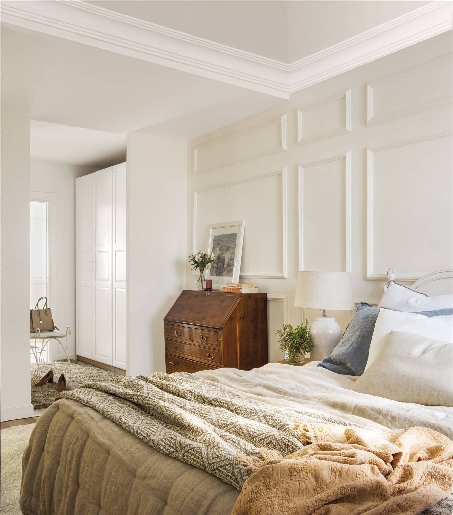 Dormitorio clásico con molduras en la pared y escritorio recuperado. 