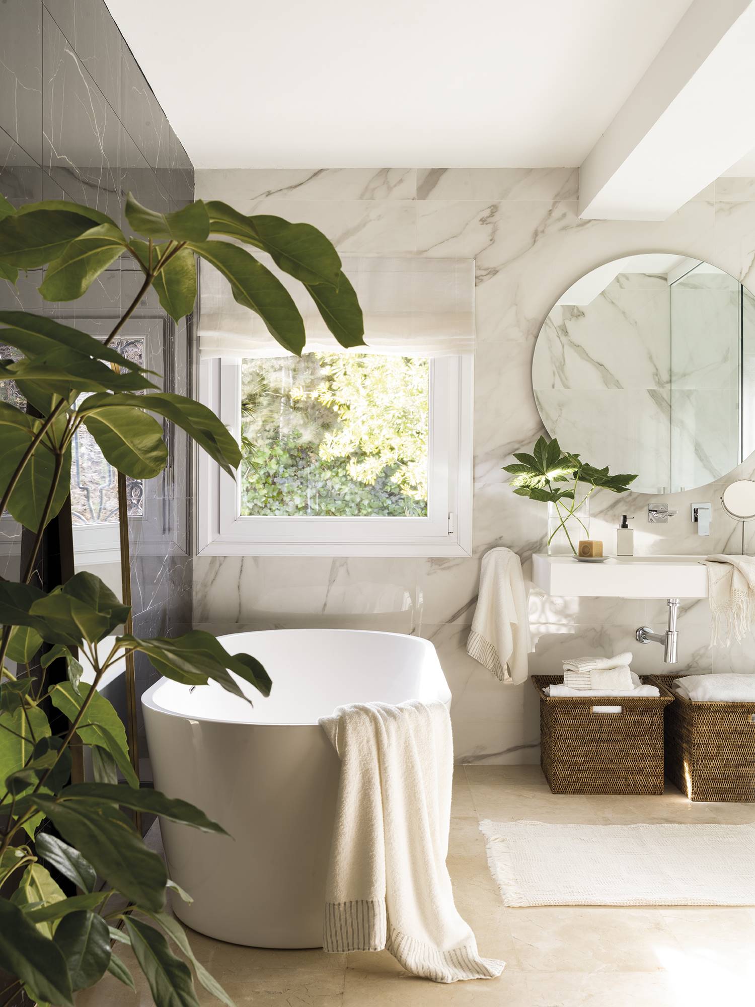 Baño con una bañera exenta y paredes de mármol. 