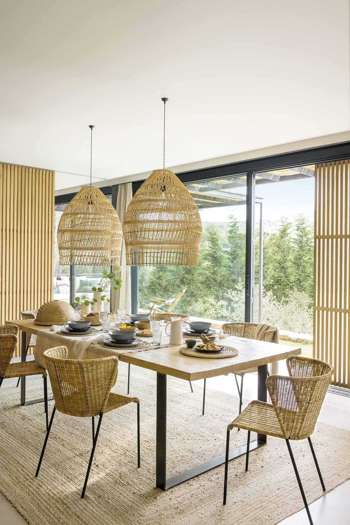 Comedor con mesa de madera y sillas y lámpara de fibras naturales. 