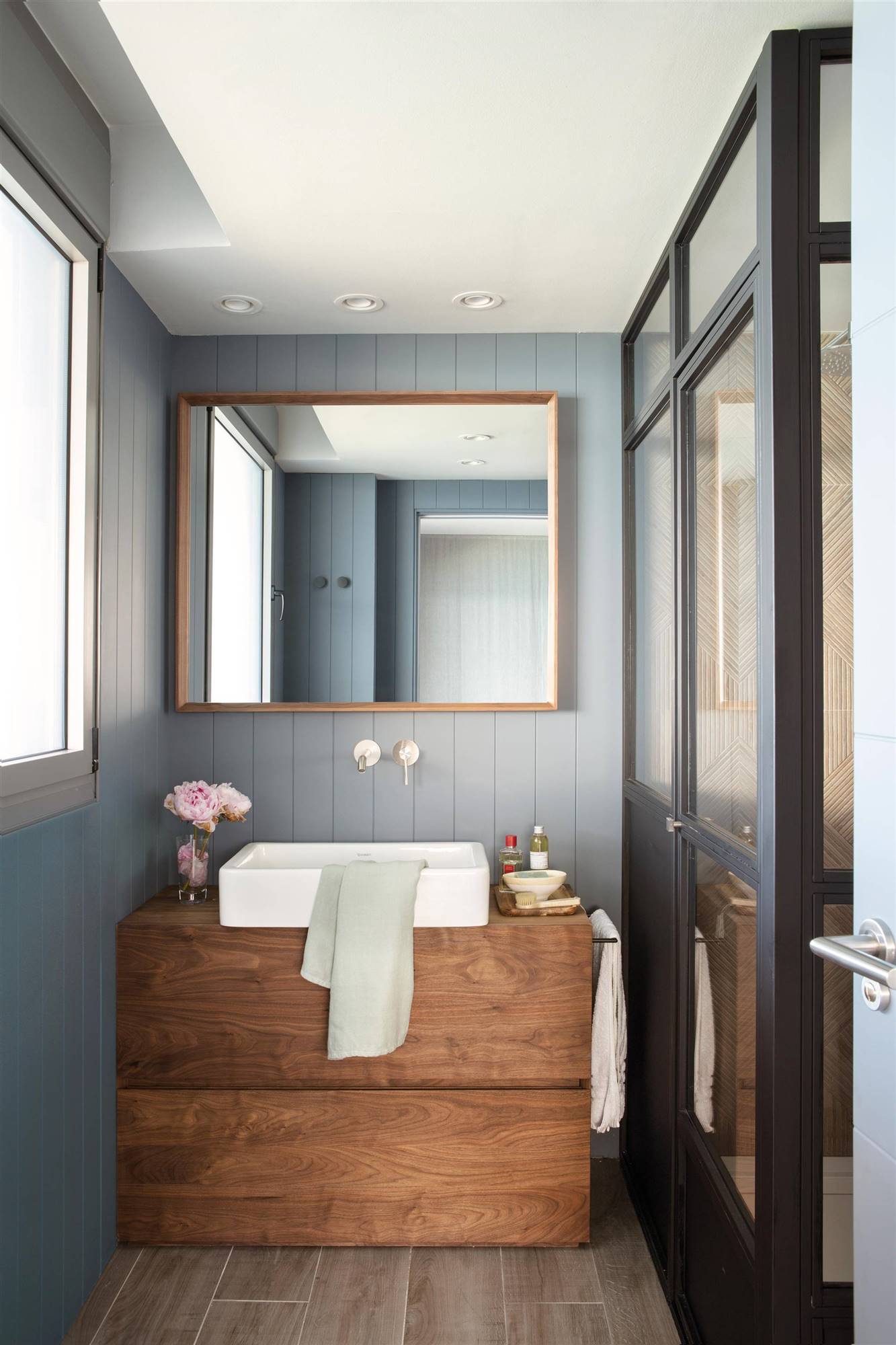 Baño pequeño moderno con paredes de madera pintadas de gris y mueble de madera. 