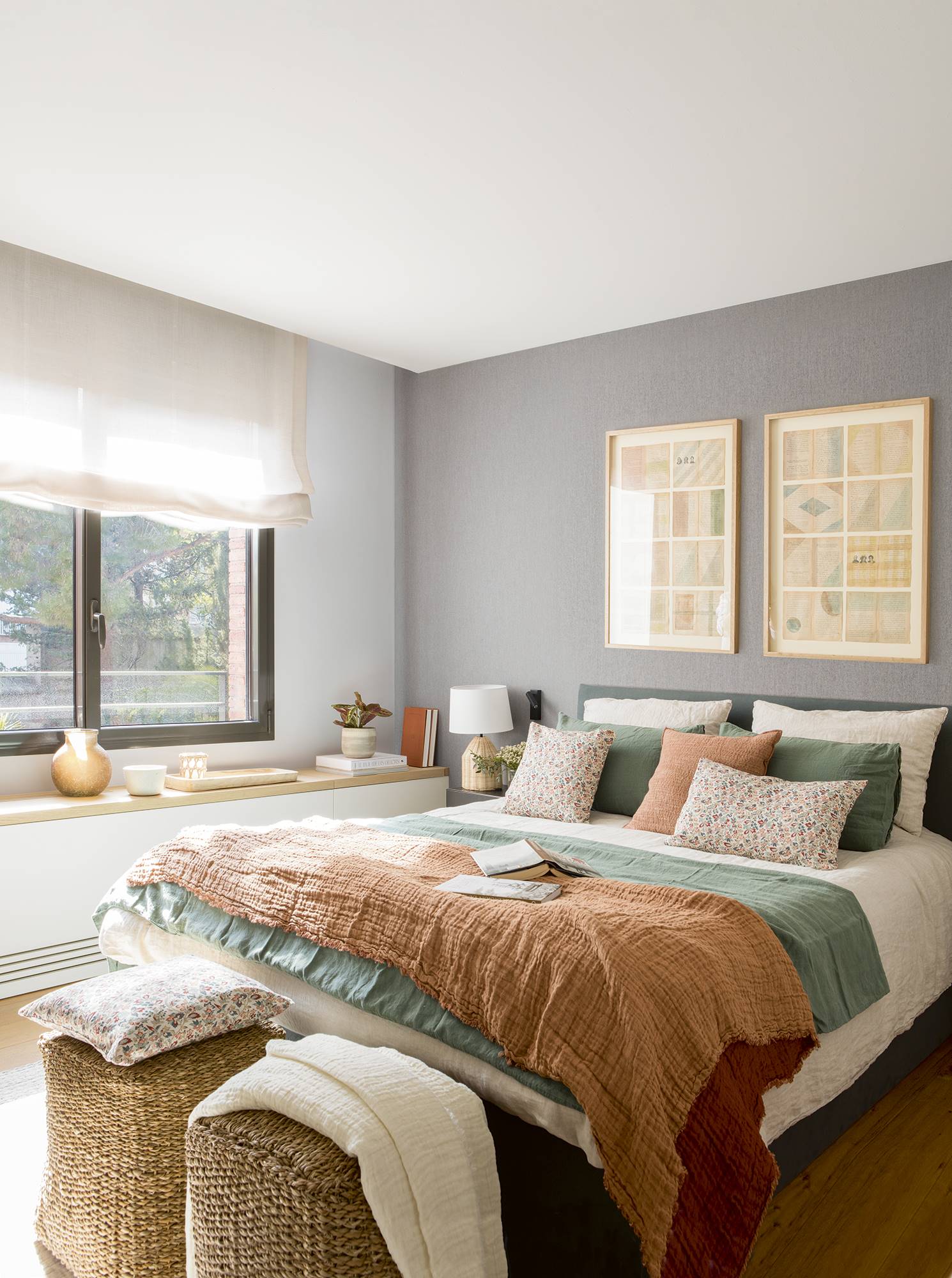 Dormitorio con cabecero tapizado, papel pintado, pufs de fibras y un mueble a medida blanco y de madera.