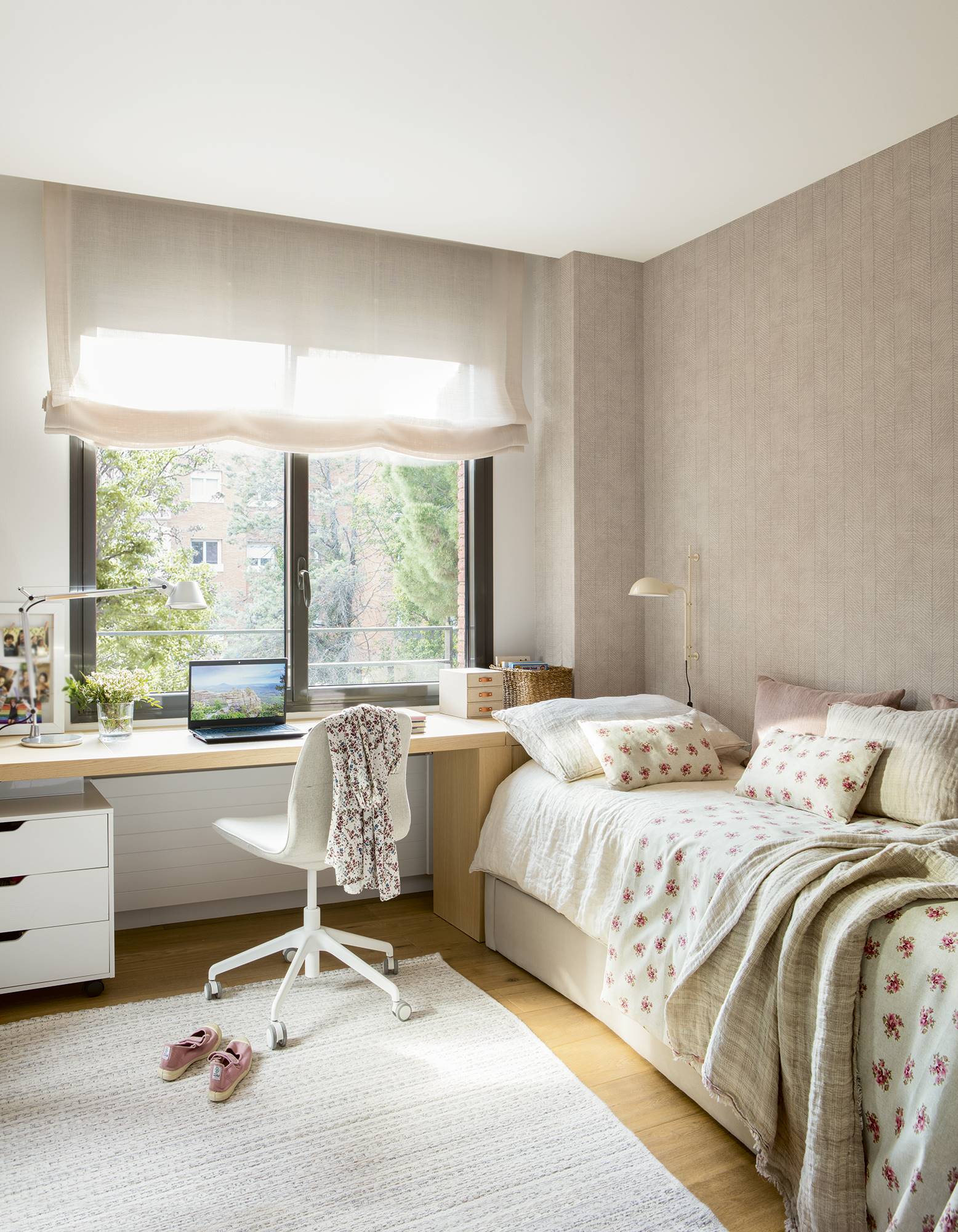 Dormitorio infantil con papel pintado en espiga y ropa de cama blanca con flores rosas.