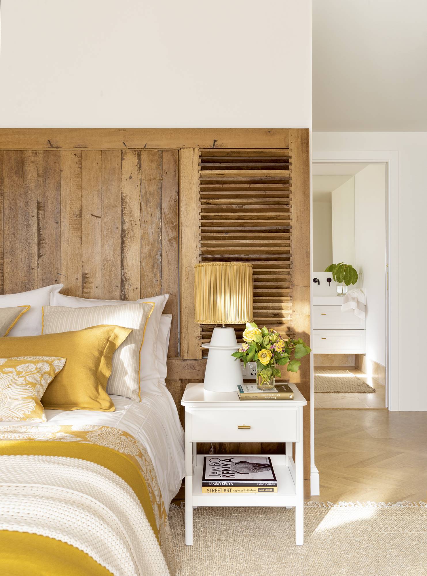 Dormitorio con gran cabecero de madera de teca.