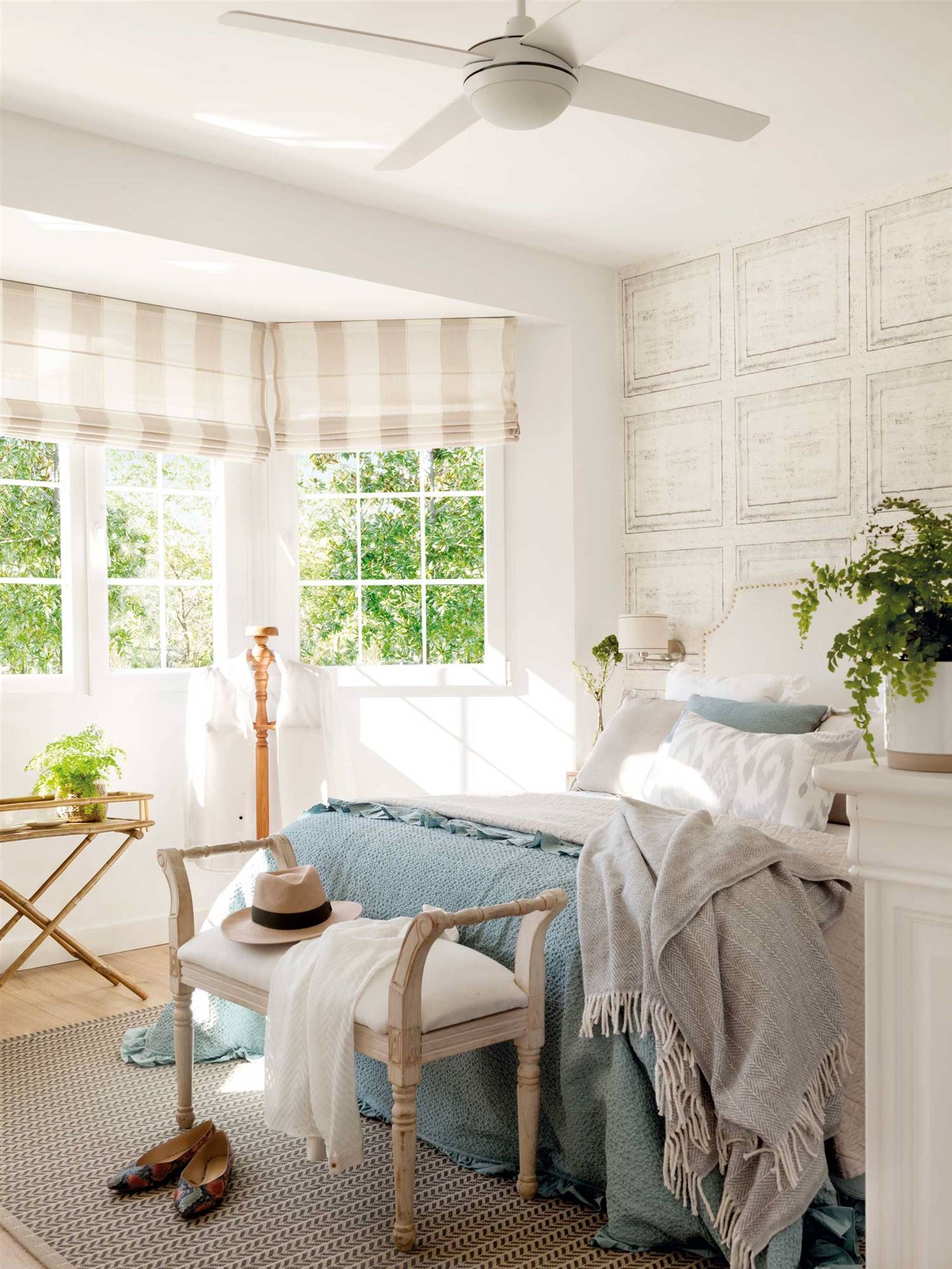 Dormitorio de verano de estilo clásico con papel pintado en la pared del cabecero y ropa de cama azul y blanca. 