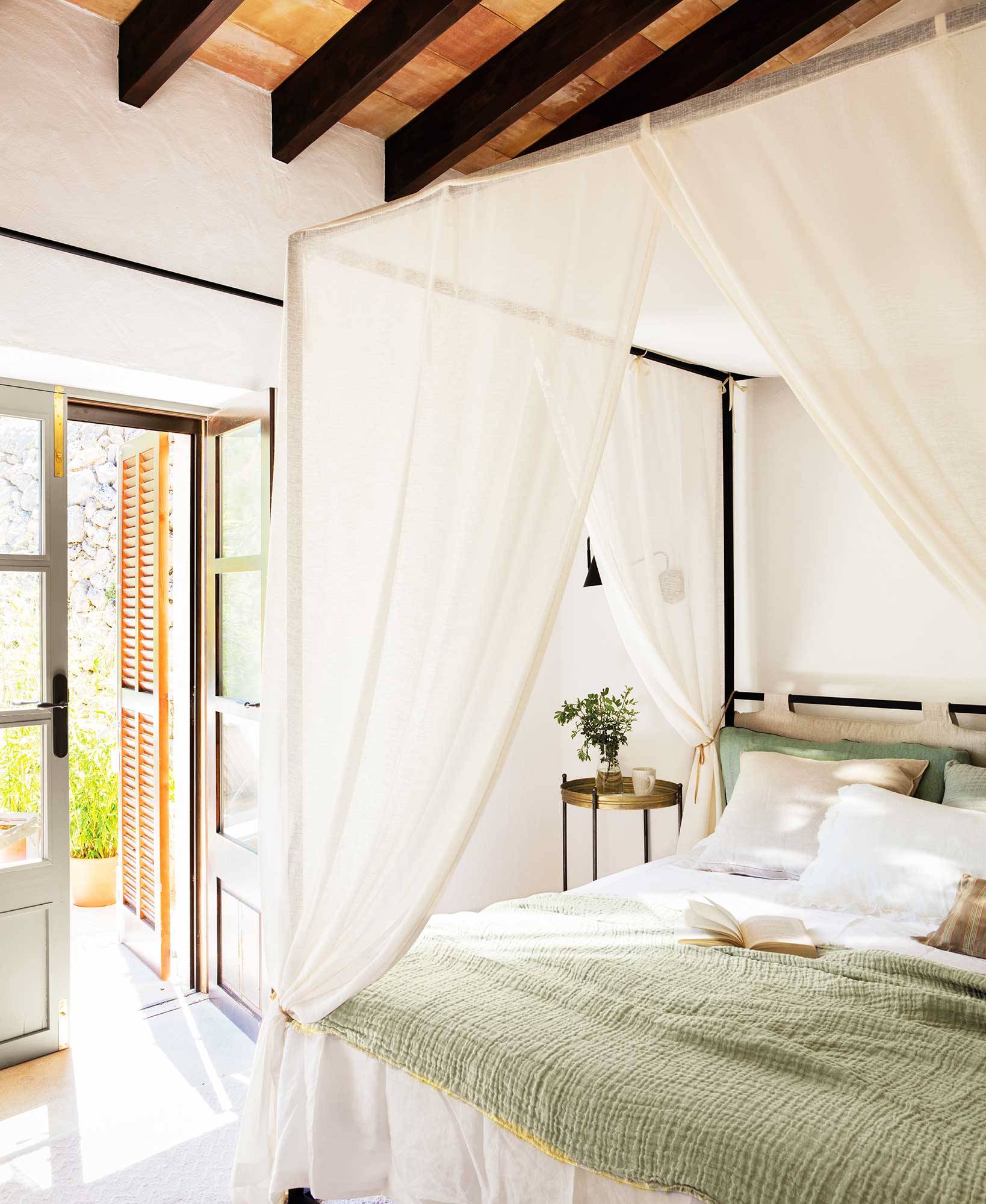 Dormitorio de verano con cama con dosel y ropa de cama de color verde. 