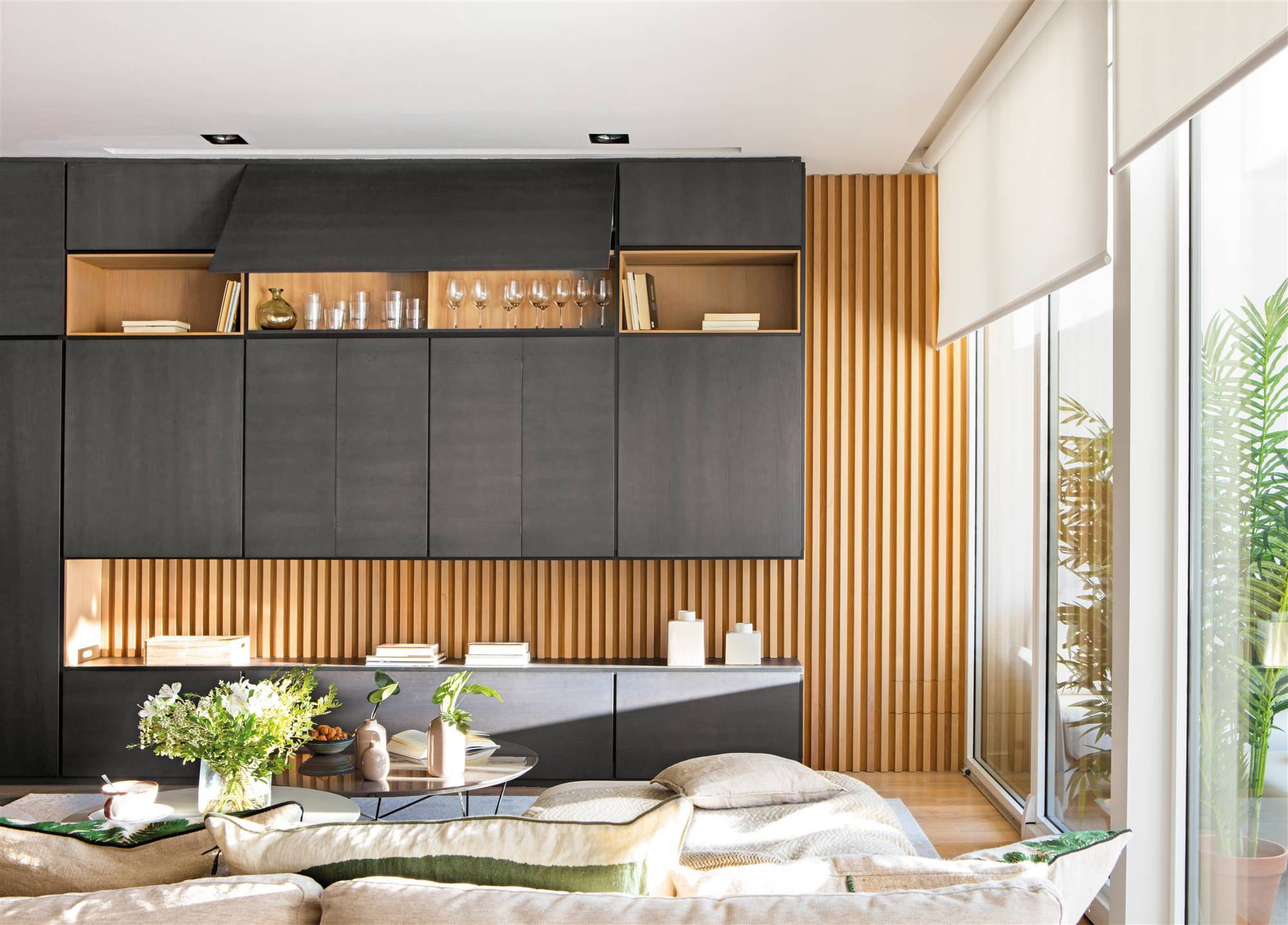 Salón con mueble diseñado a medida en negro on palillería de madera detrás. 
