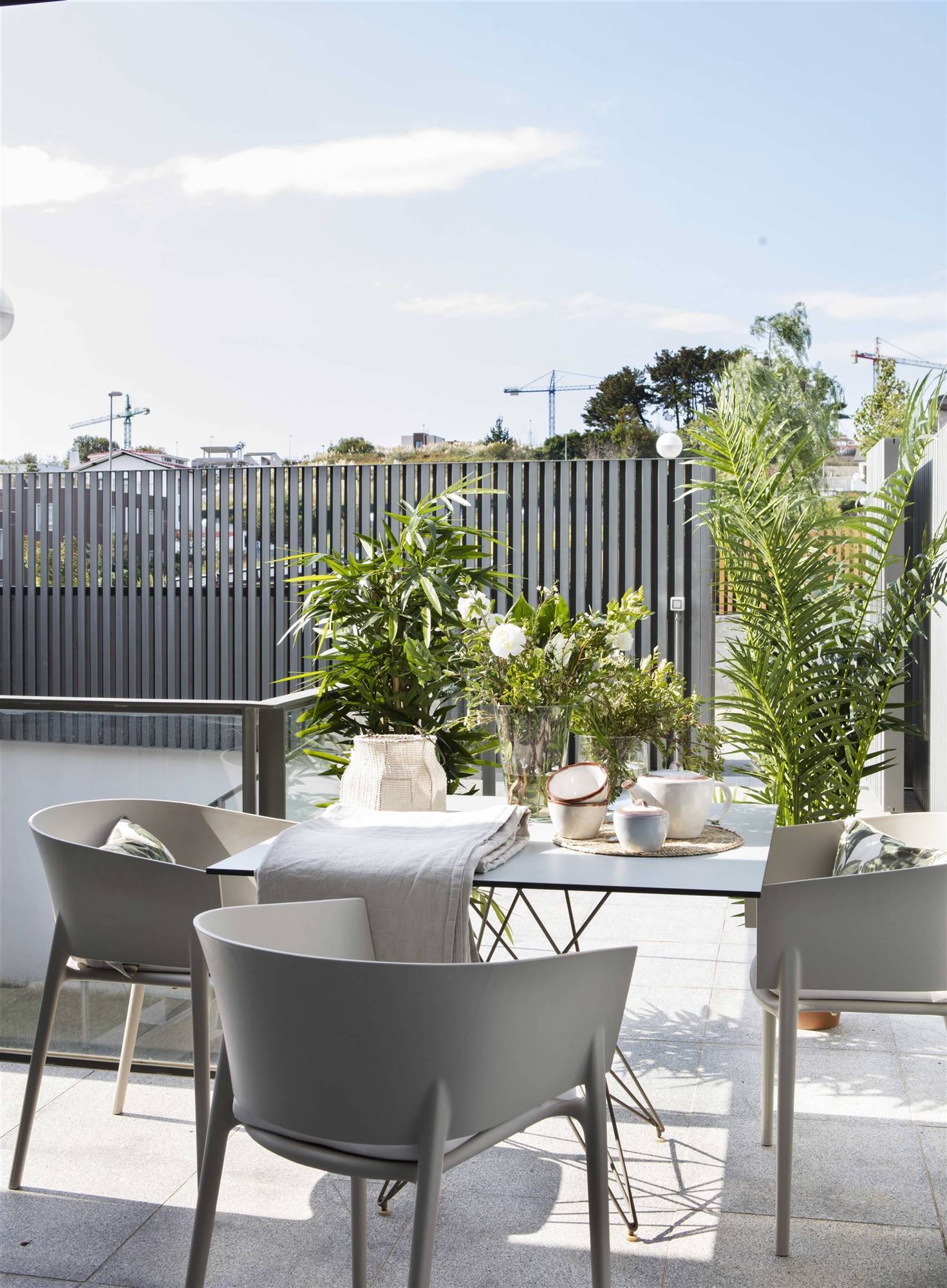 Terraza moderna con comedor exterior con sillas grises, mesa y plantas de exterior. 