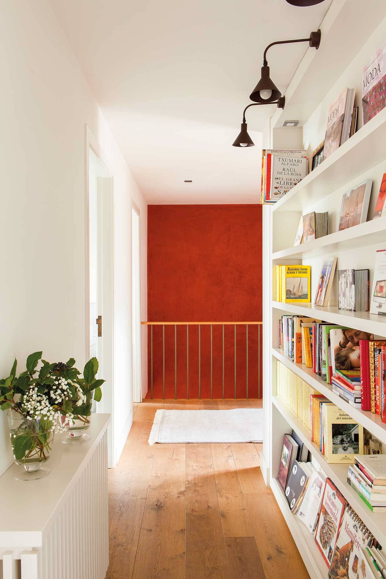 Pasillo con encanto decorado con una estantería y la pared del fondo de color rojo. 
