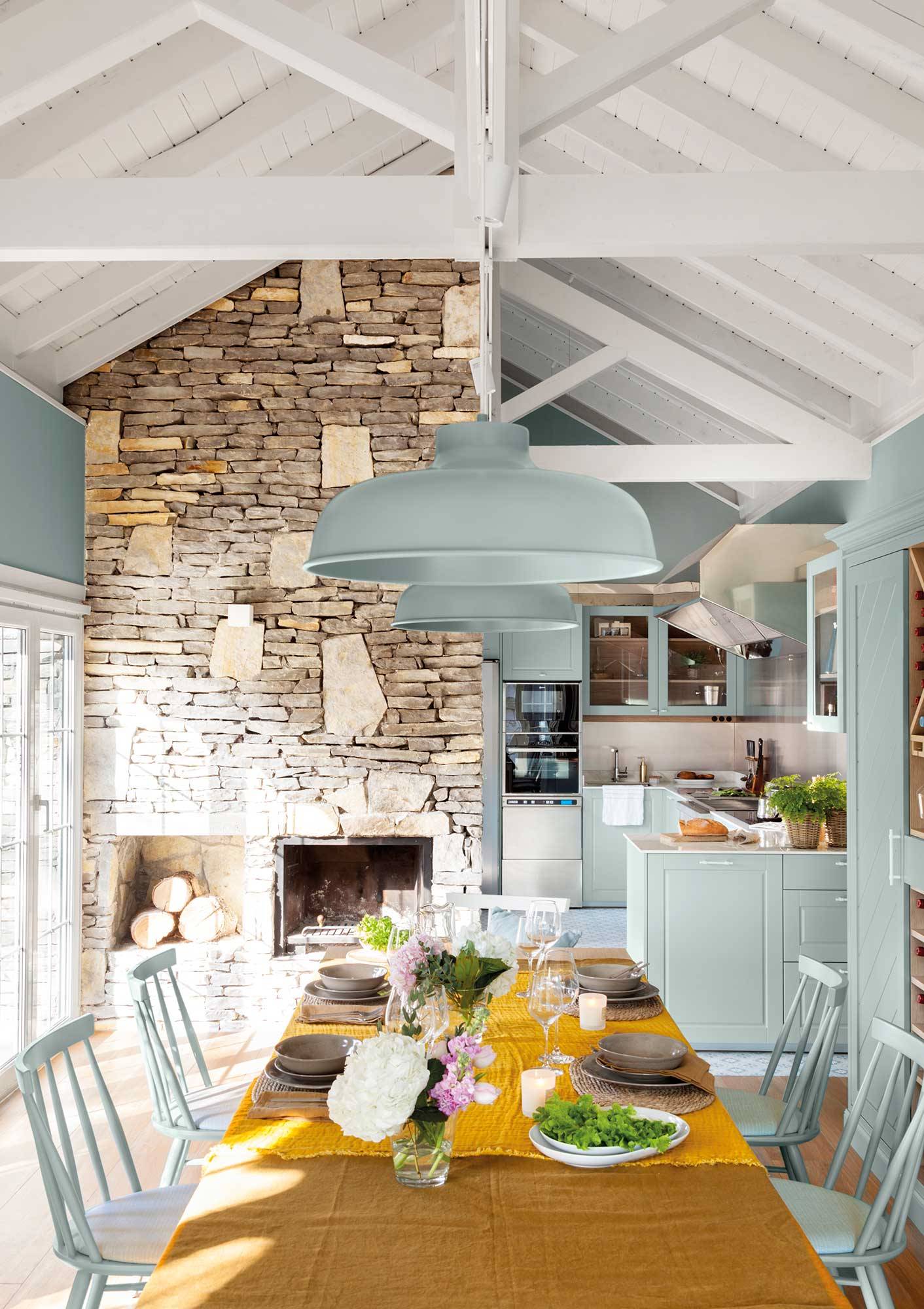 Cocina rústica moderna con paredes de piedra y lámparas en azul cielo. 