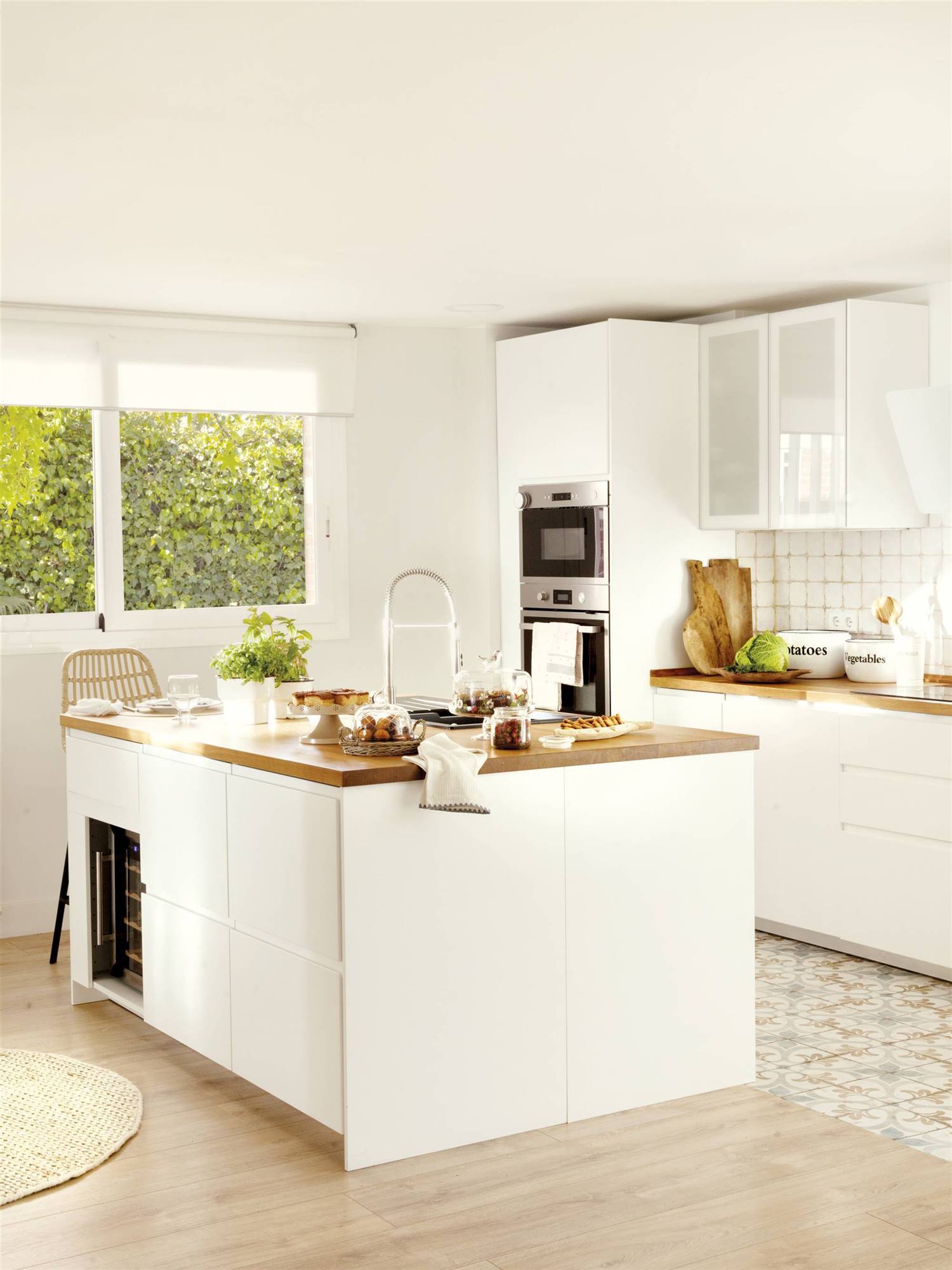 Cocina blanca moderna con encimera de madera y suelos de porcelánicos de madera y acabado hidráulico. 