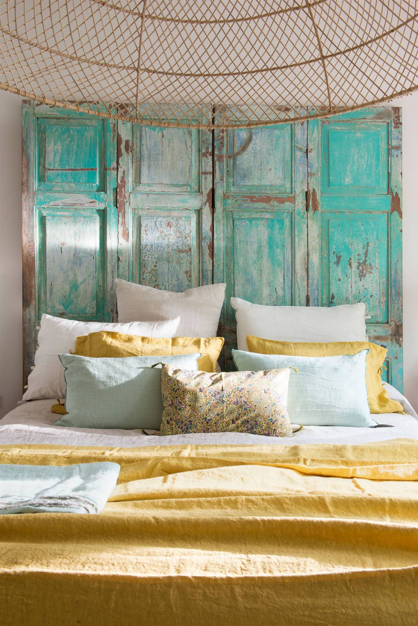 Dormitorio con colcha de verano de color mostaza y cabecero recuperado.  
