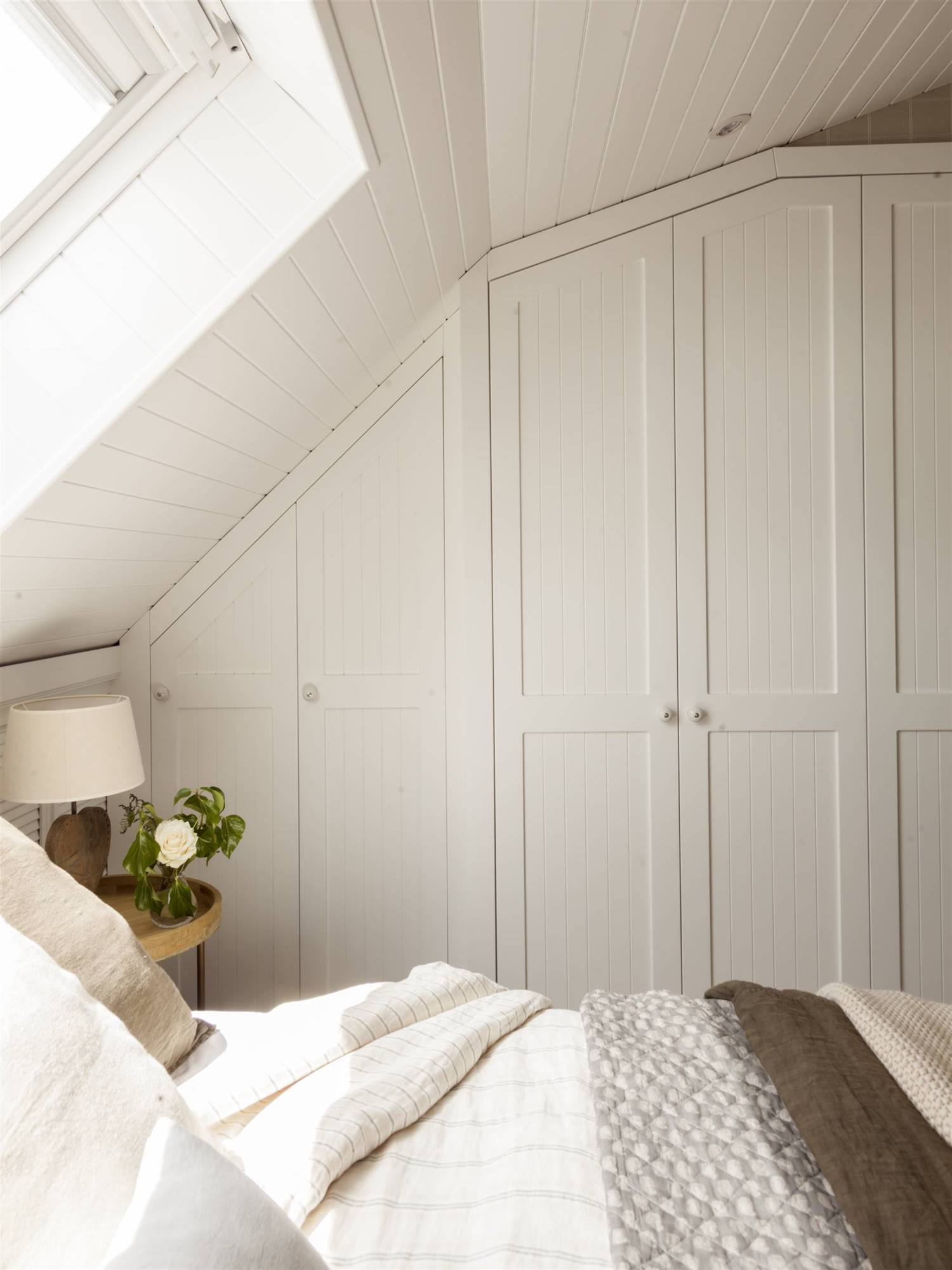 Dormitorio con armario con puertas escamoteables blancas. 