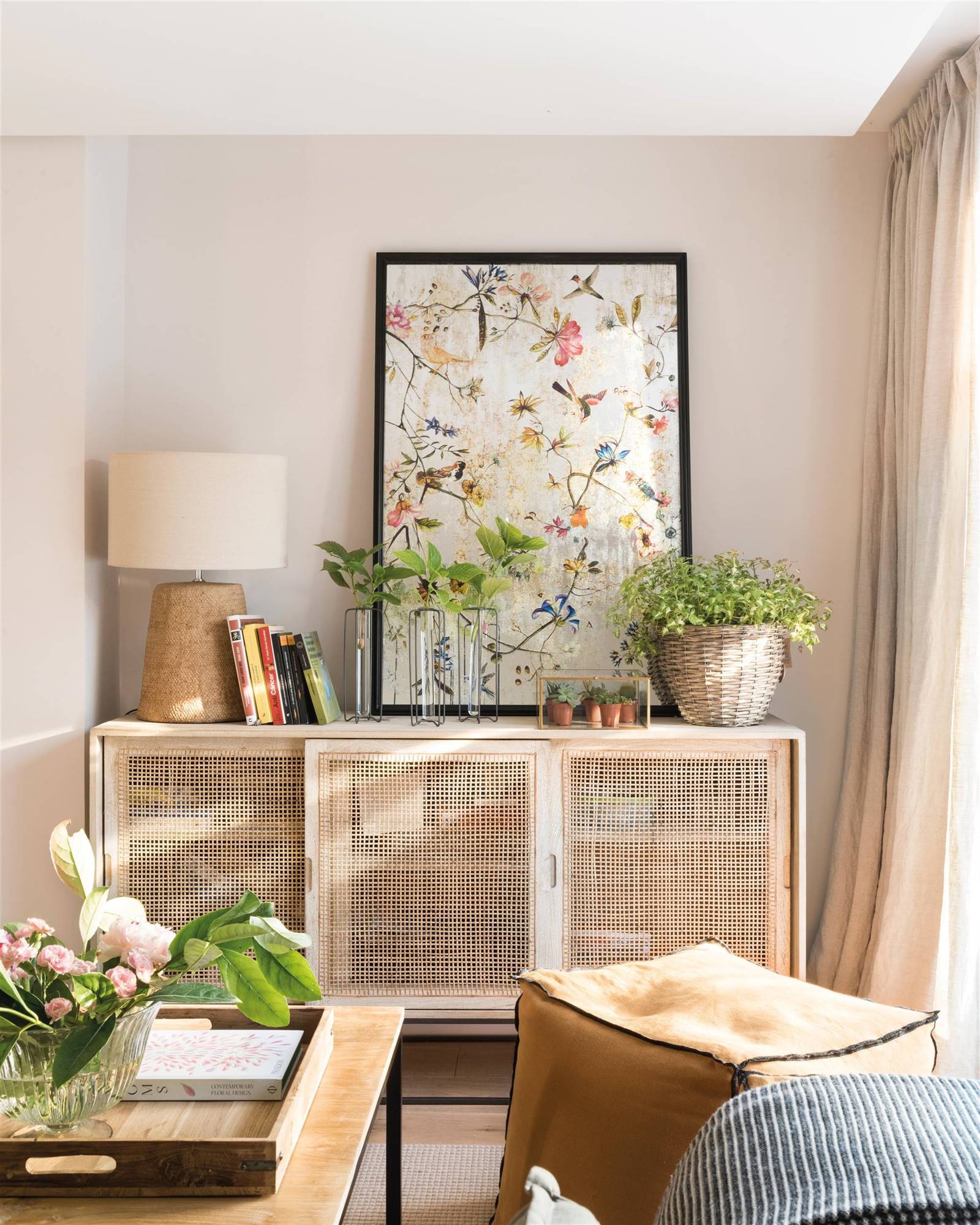 Aparador con puertas de rejilla decorado con un cuadro, una lámpara de mesa y plantas. 