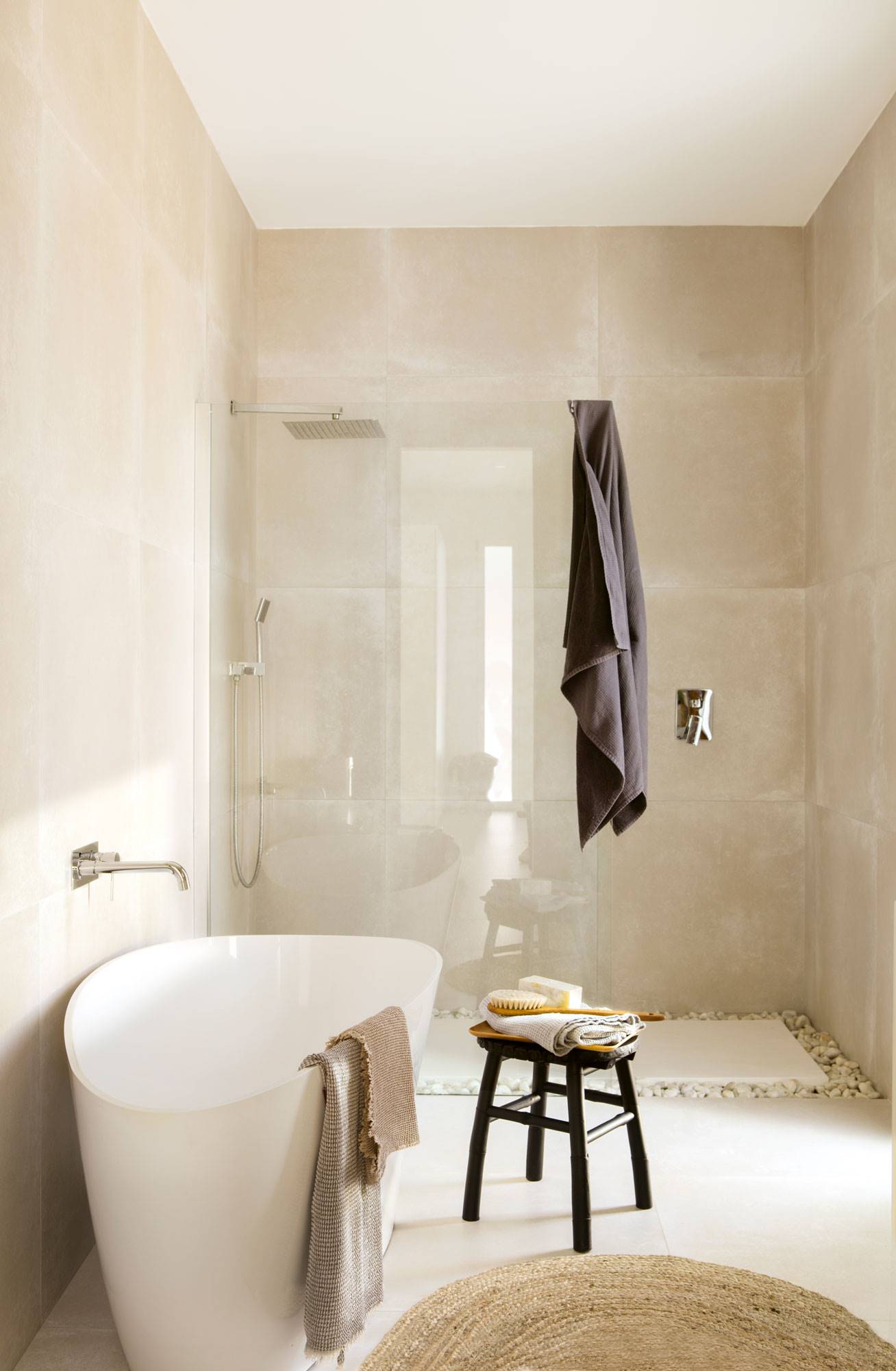 Bano con bañera exenta, ducha con panel fijo y taburete bajo de color negro. 