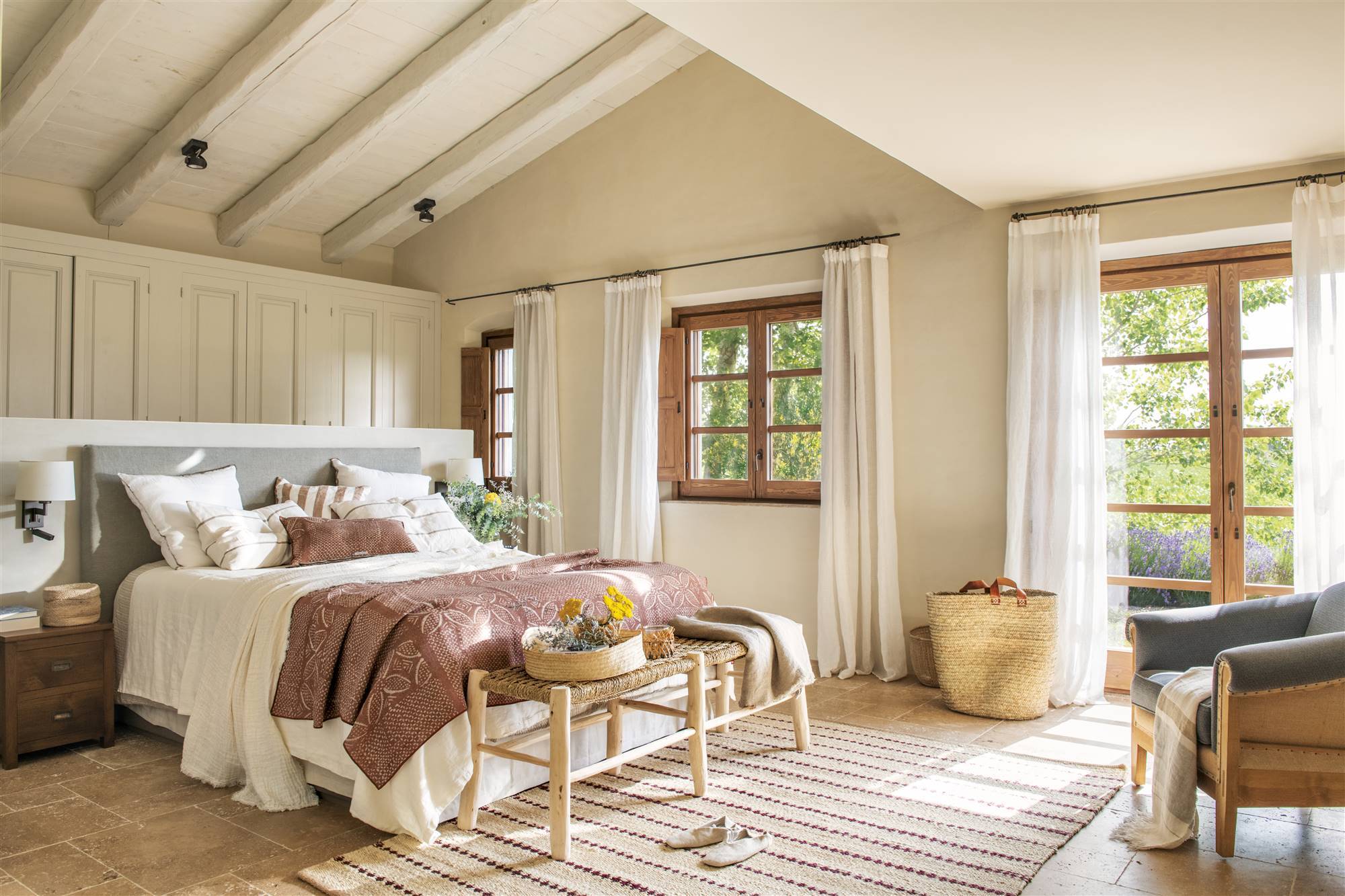 Dormitorio de verano de estilo campestre con vestidor tras el cabecero y ropa de cama blanca y terracota. 