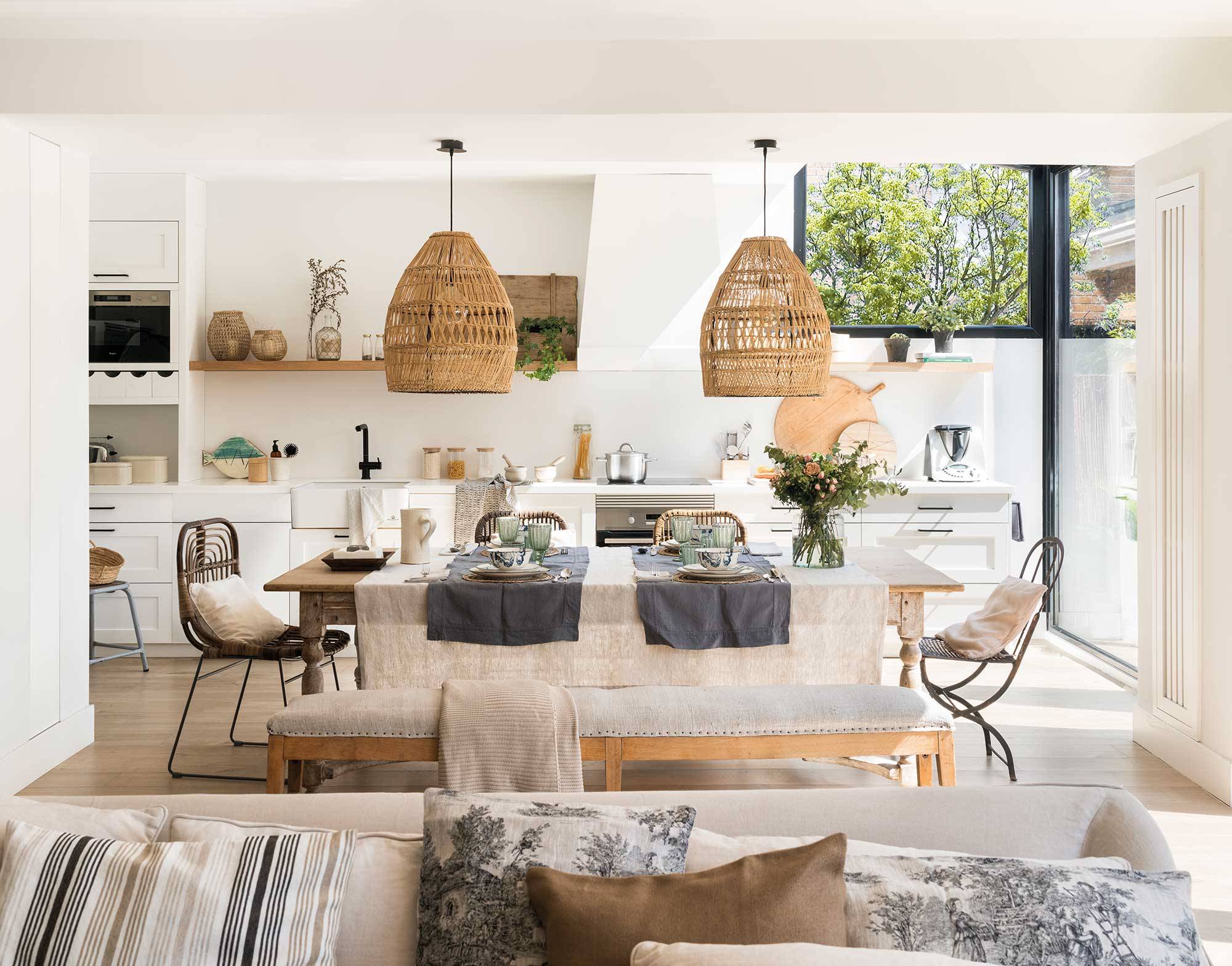 Salón abierto a la cocina decorado por Asun Antó con un estilo ibicenco, sofás blancos y lámparas de fibra.