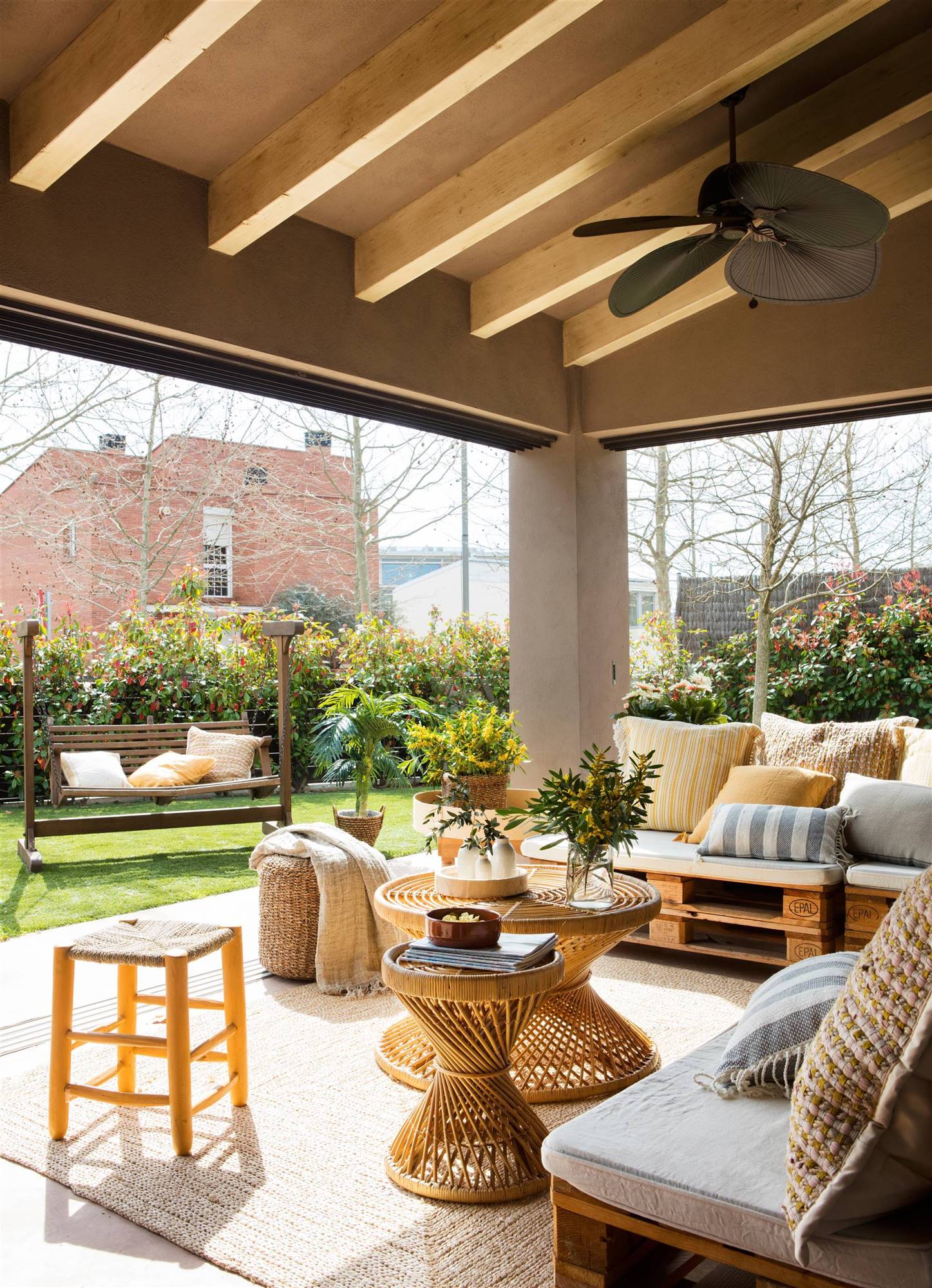 Zona chill out en porche con sofás de palets y mesas de centro redondas de fibra retorcida