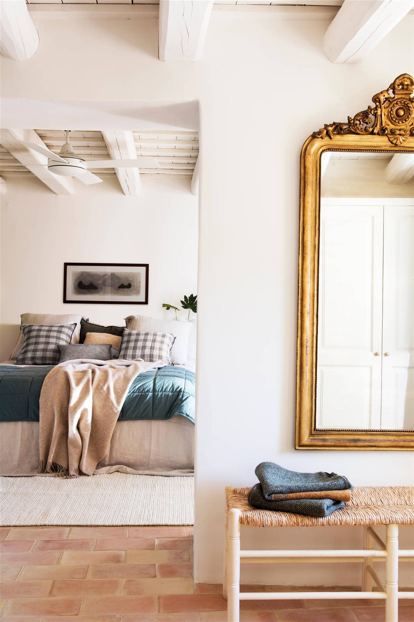 Vestidor con espejo de pared dorado y banco integrado en el dormitorio
