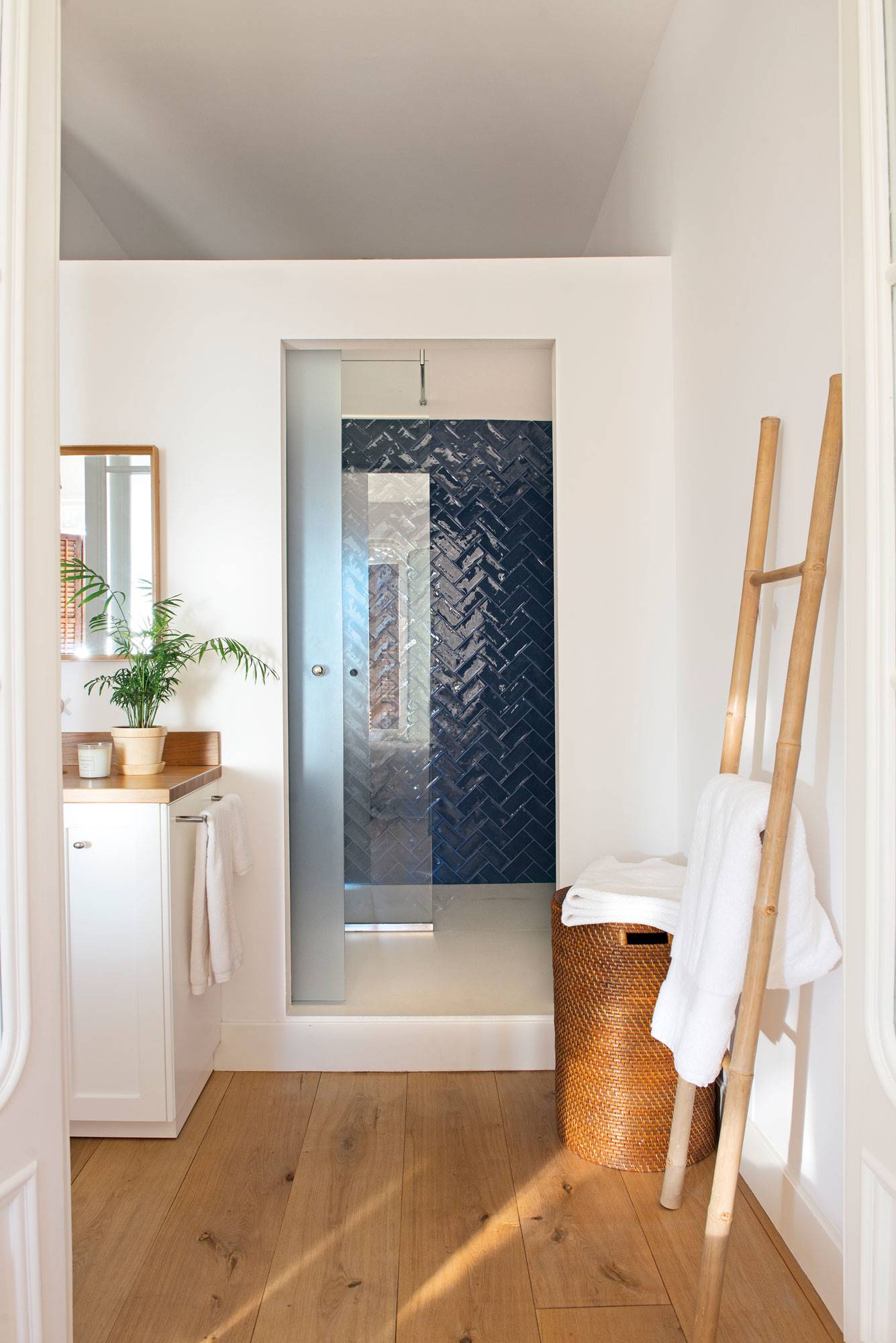 Baño con ducha con puerta corredera y azulejos en azul con acabado brillante. 