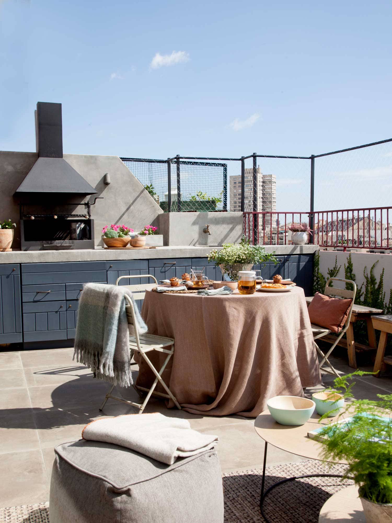 Terraza con cocina al aire libre junto al comedor exterior.