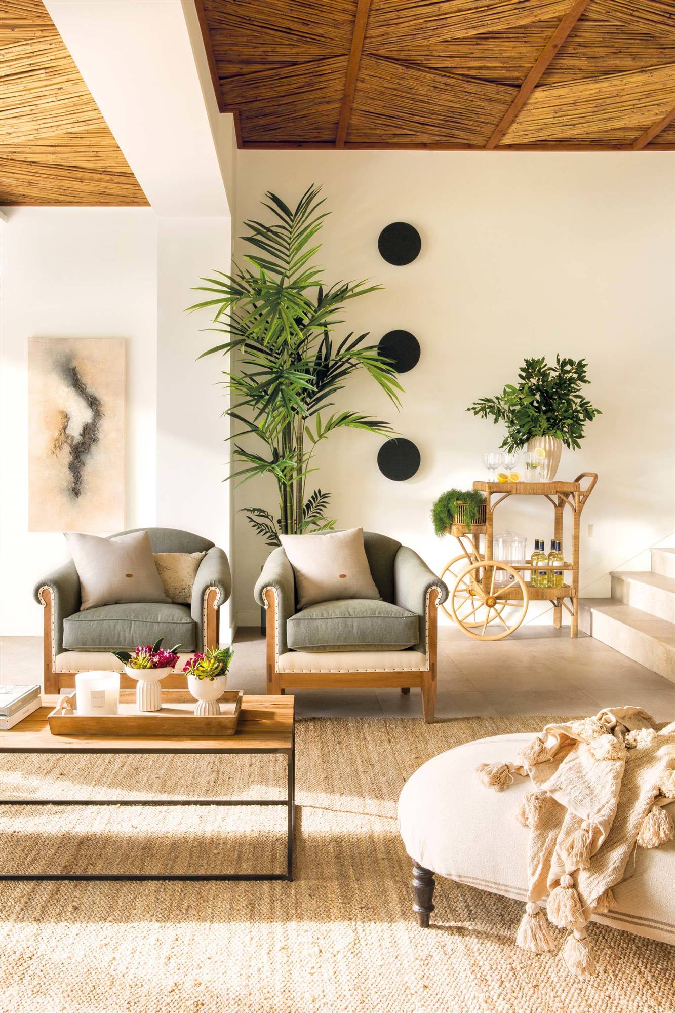 Salón veraniego con plantas y muebles de fibras naturales. 