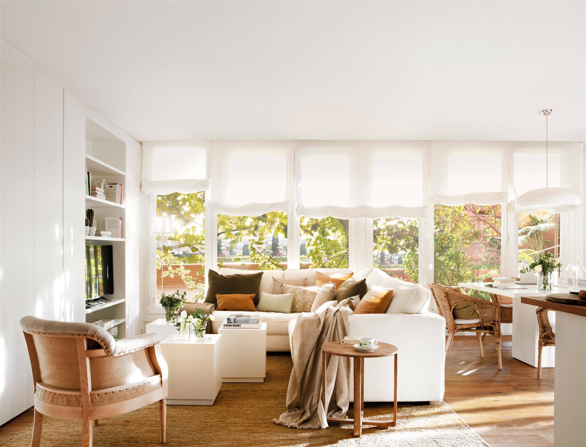 Salón moderno con sofá blanco en L, ventanal y mueble que oculta la televisión