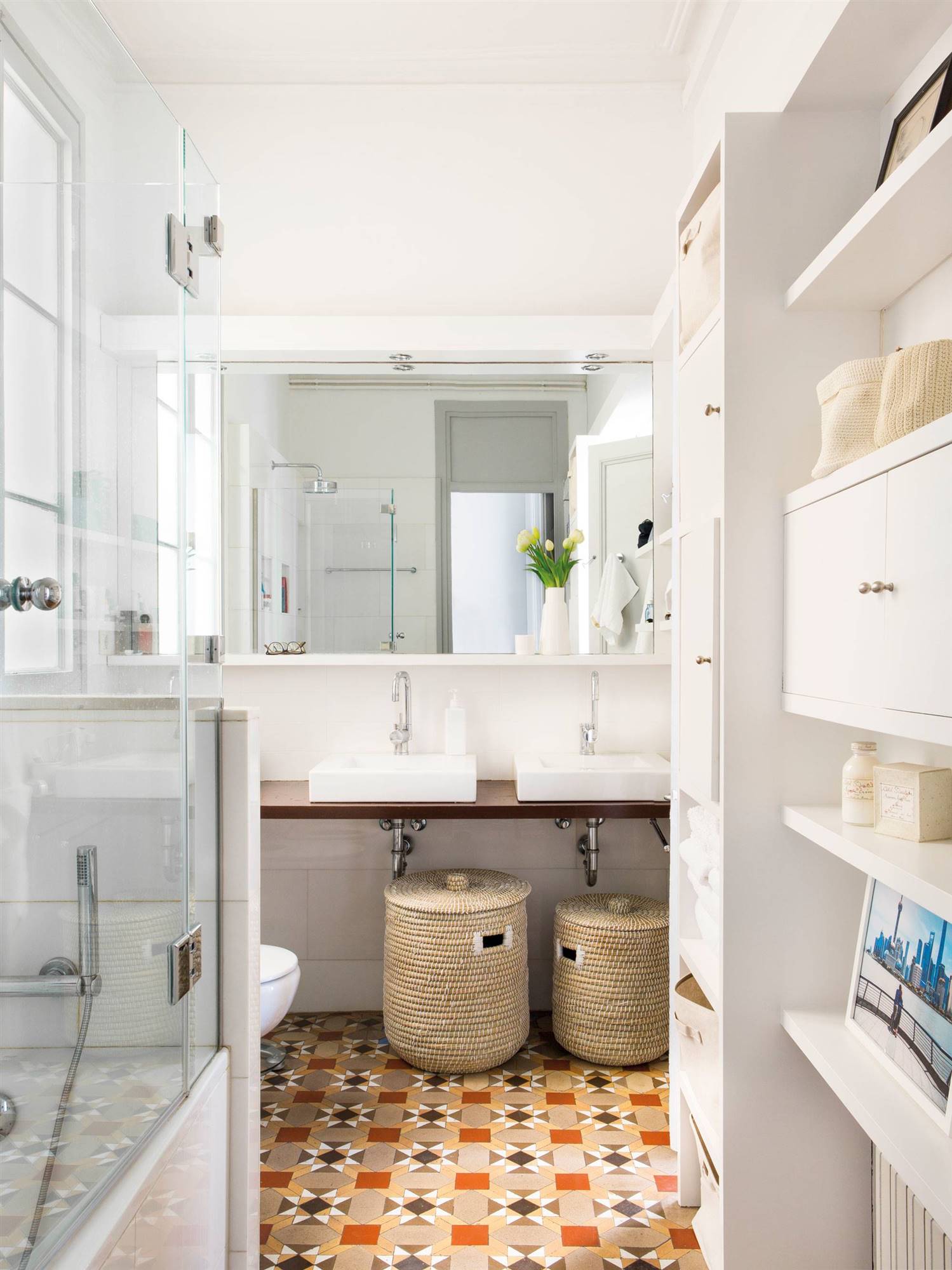 Baño con muebles blancos y suelo de mosaico hidráulico.