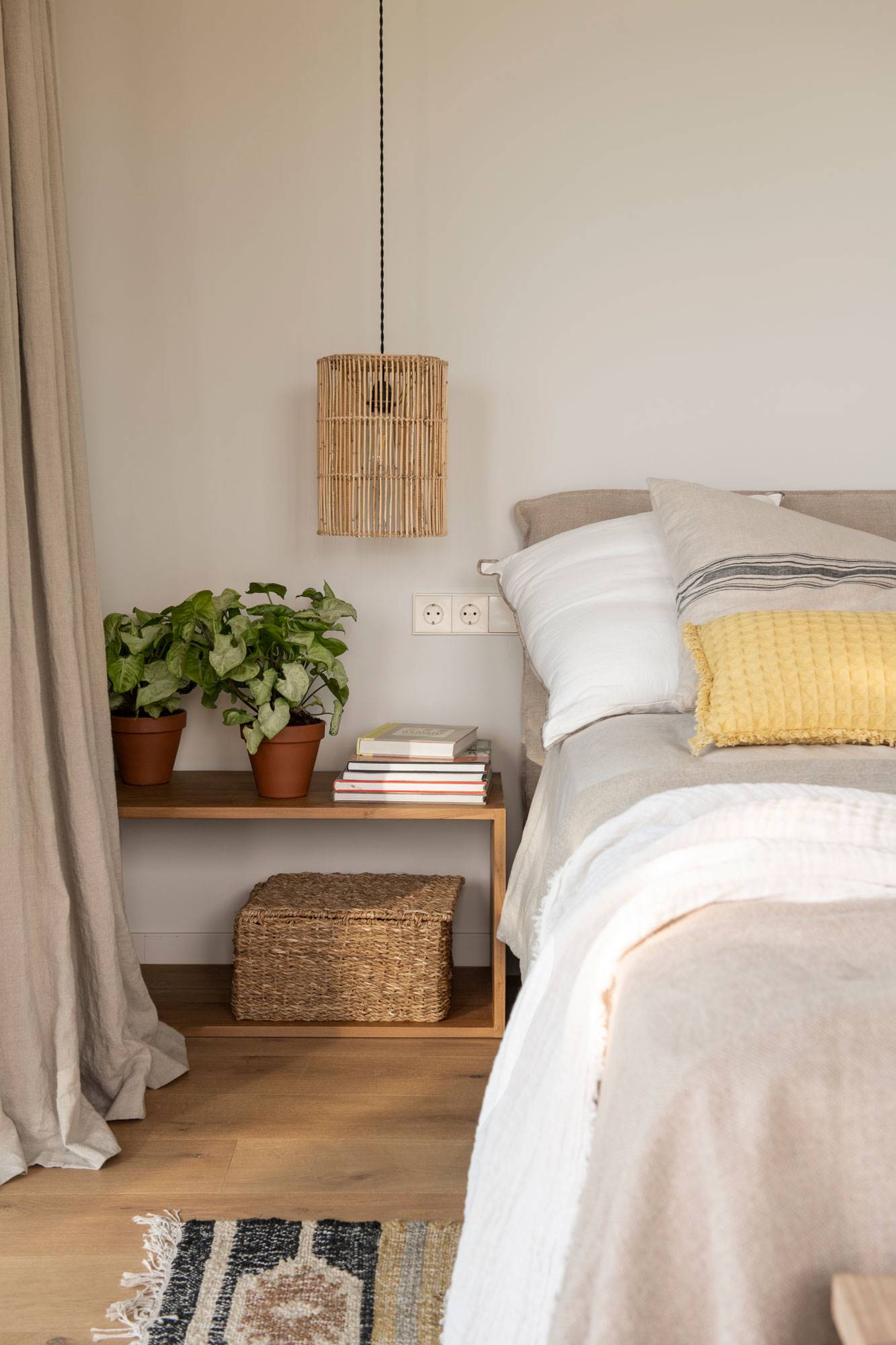 Dormitorio con mesilla de madera y lámpara de fibra.