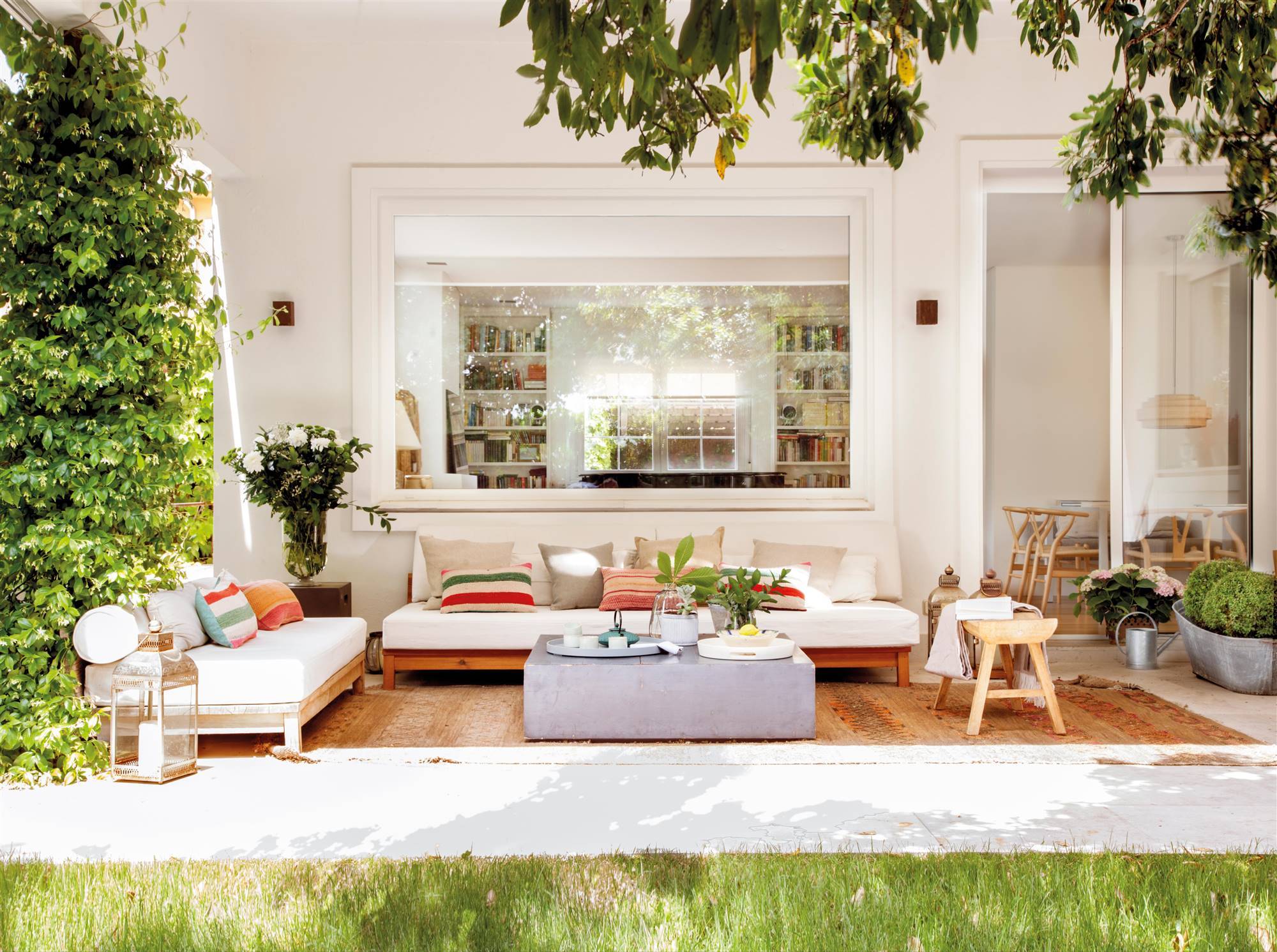 Zona chill out en porche en blanco de estilo moderno y con alfombras étnicas.