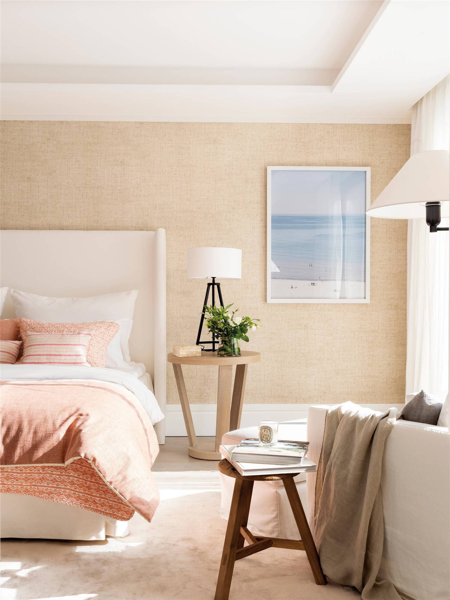 Dormitorio con cabecero tapizado en blanco y orejero.