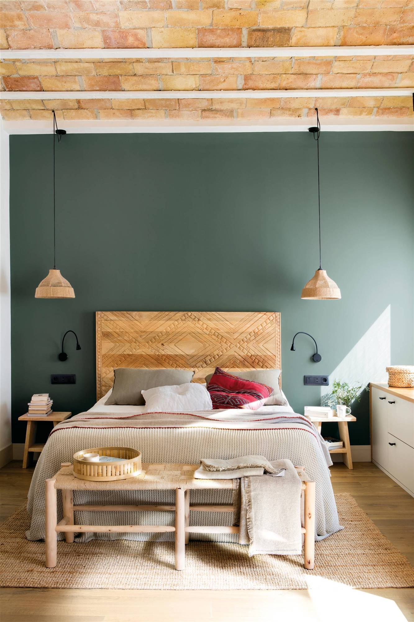  Dormitorio con cabecero de madera tallada y pared pintada en verde.