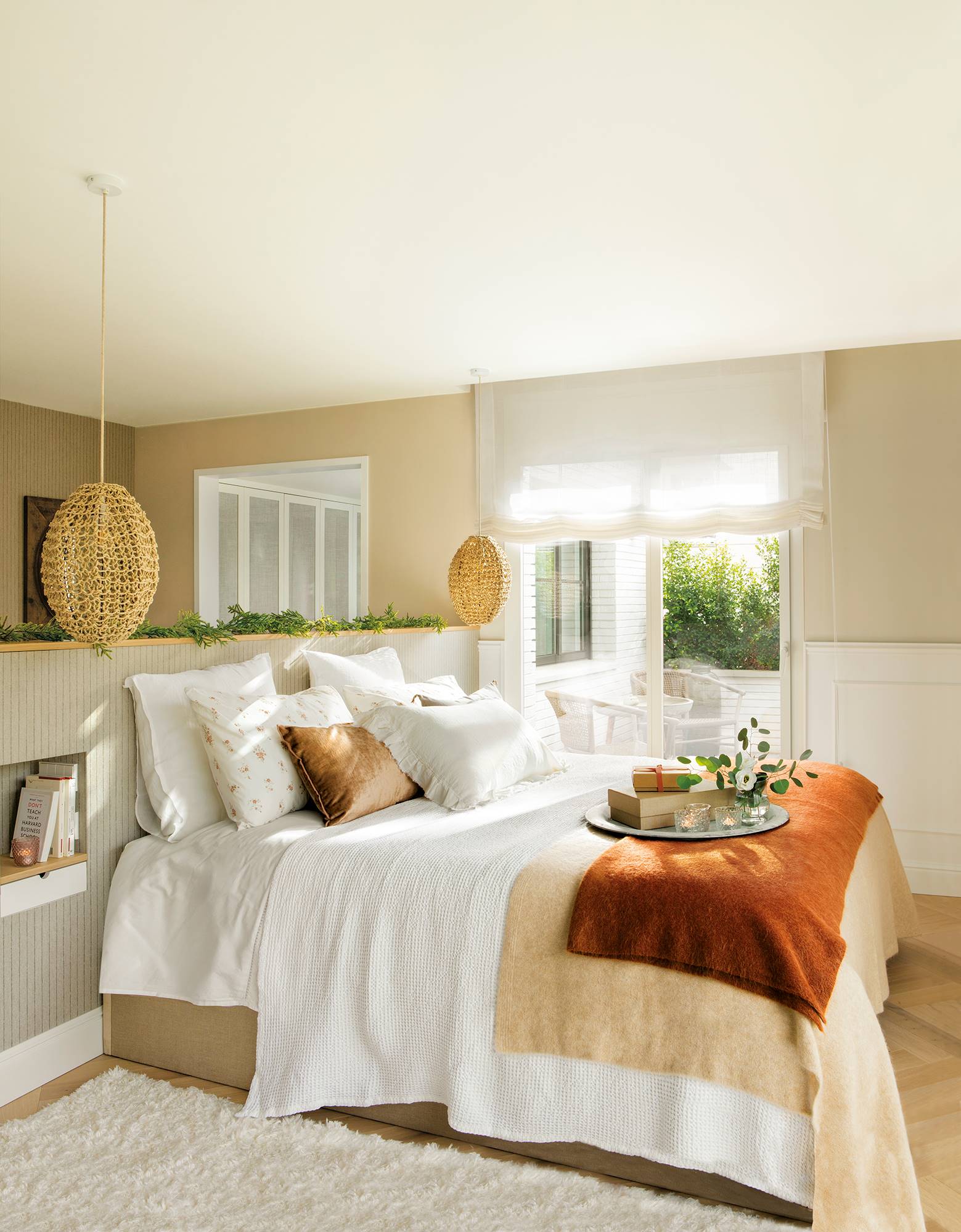 Dormitorio con cabecero en forma de murete revestido de papel pintado a rayas y lámparas colgantes de fibra.