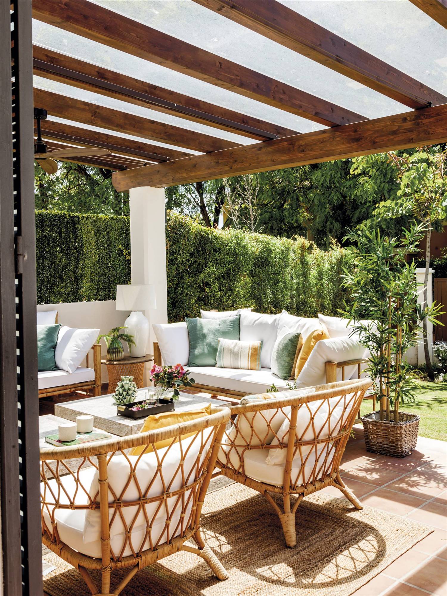 Terraza en un jardín con fibras, sillas de ratán y cojines en azul. 