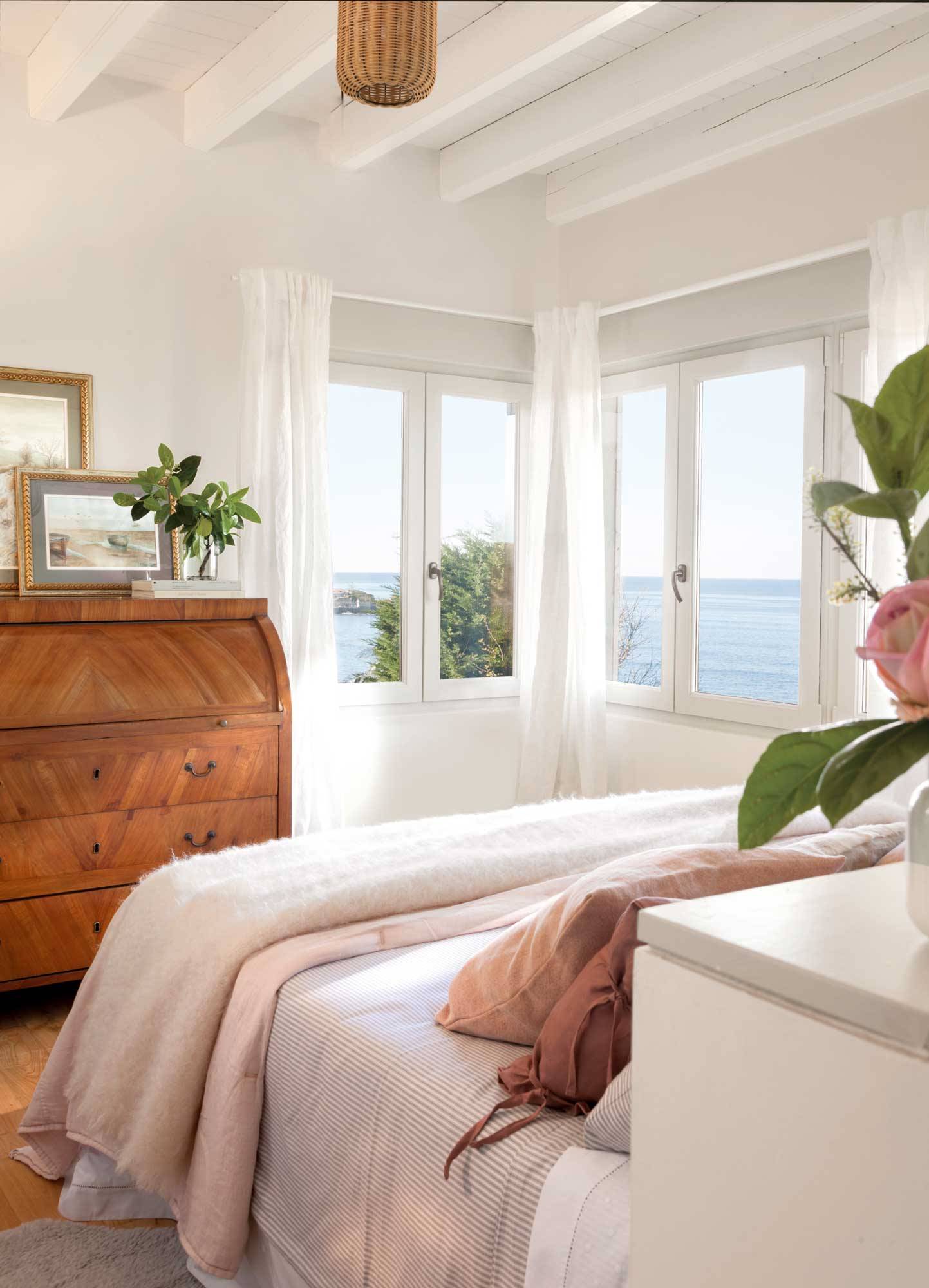Dormitorio veraniego con toques de rosa pastel y grandes vistas al mar