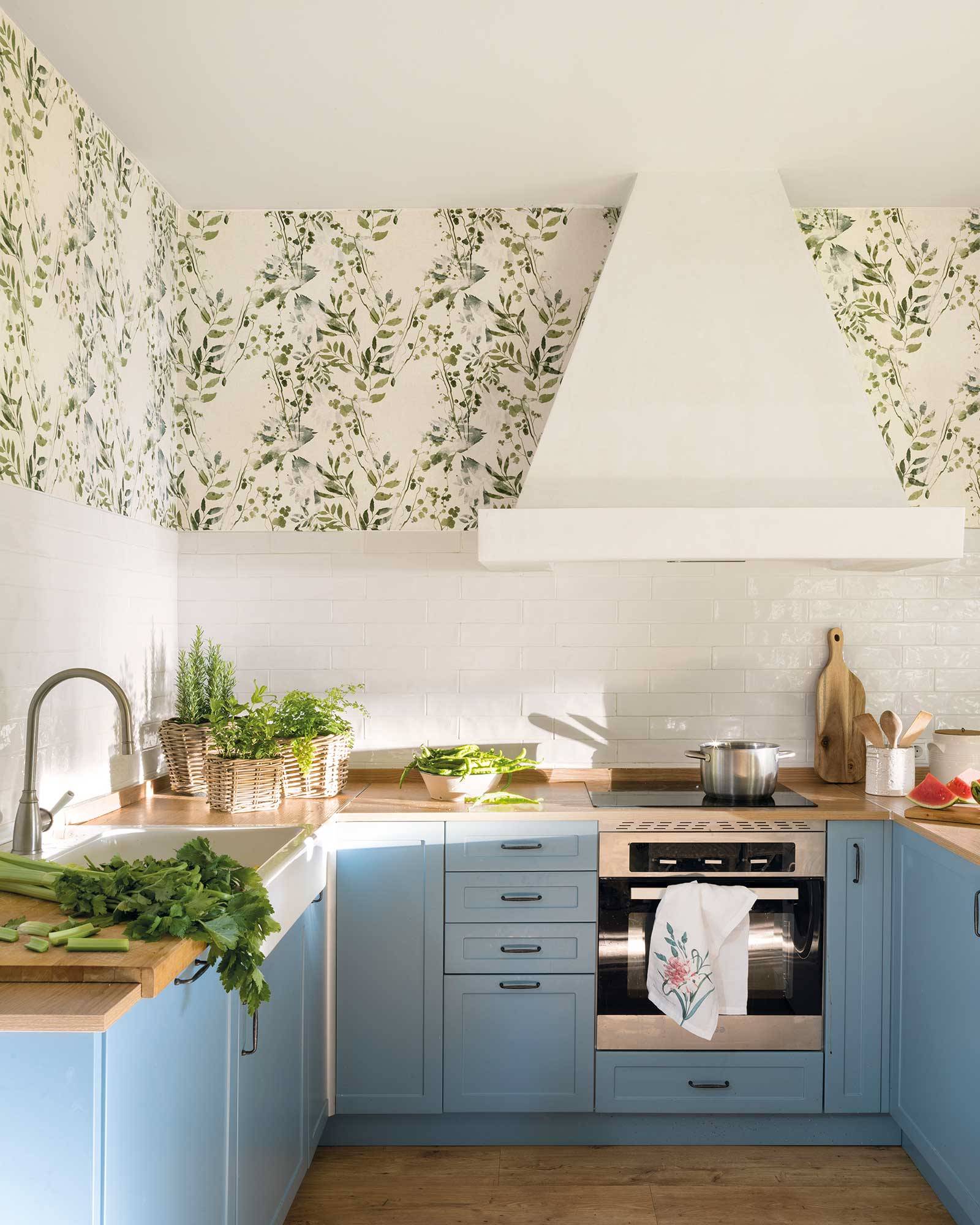 Cocina pequeña de estilo vintage con armarios en color azul y papel pintado botánico.