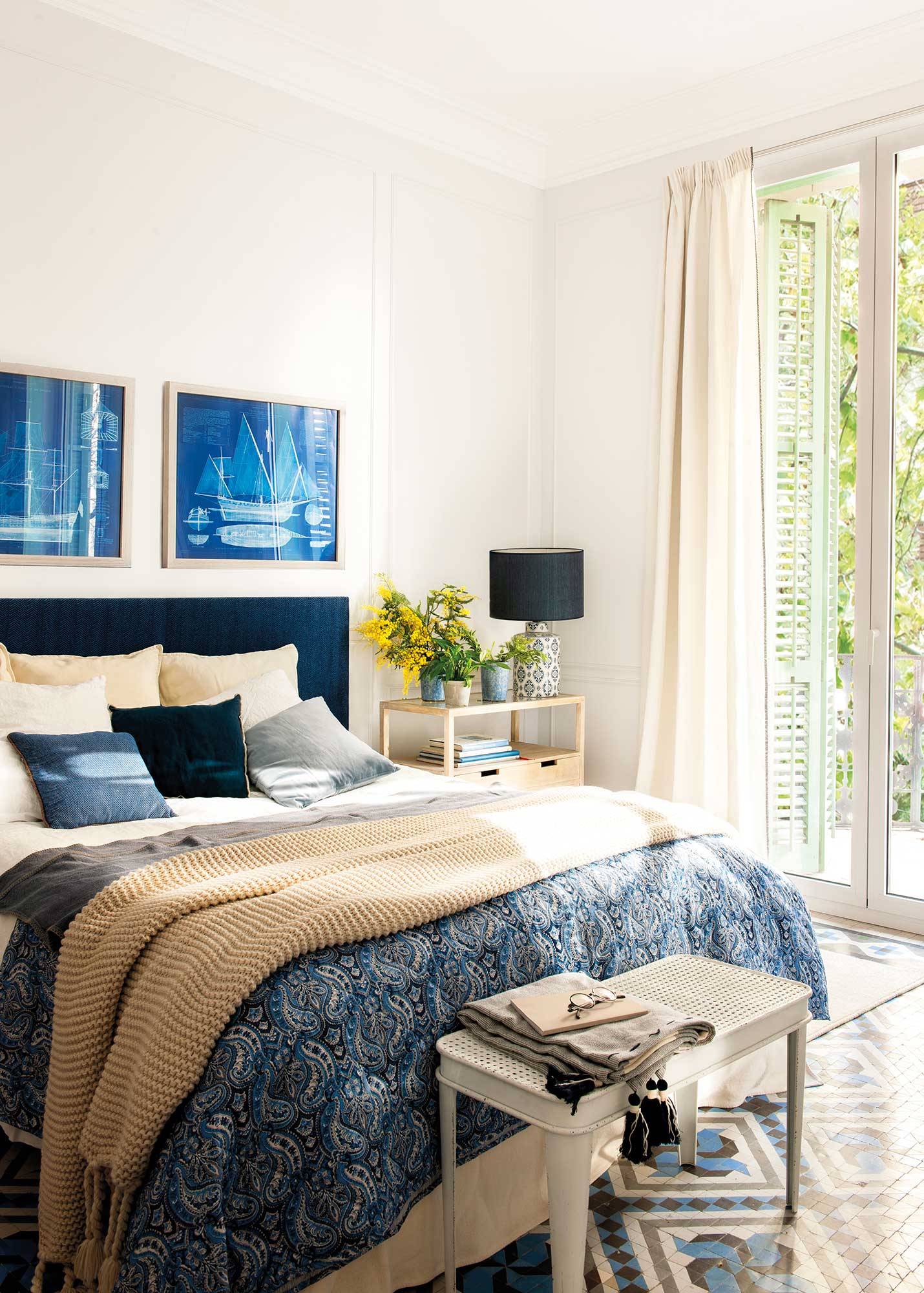 Dormitorio con cabecero y ropa de cama azul y colcha azul. 