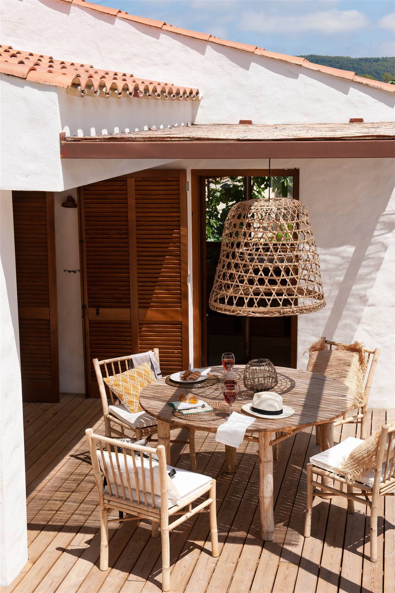 Terraza con comedor exterior con sillas de bambu y lámpara de fibras. 