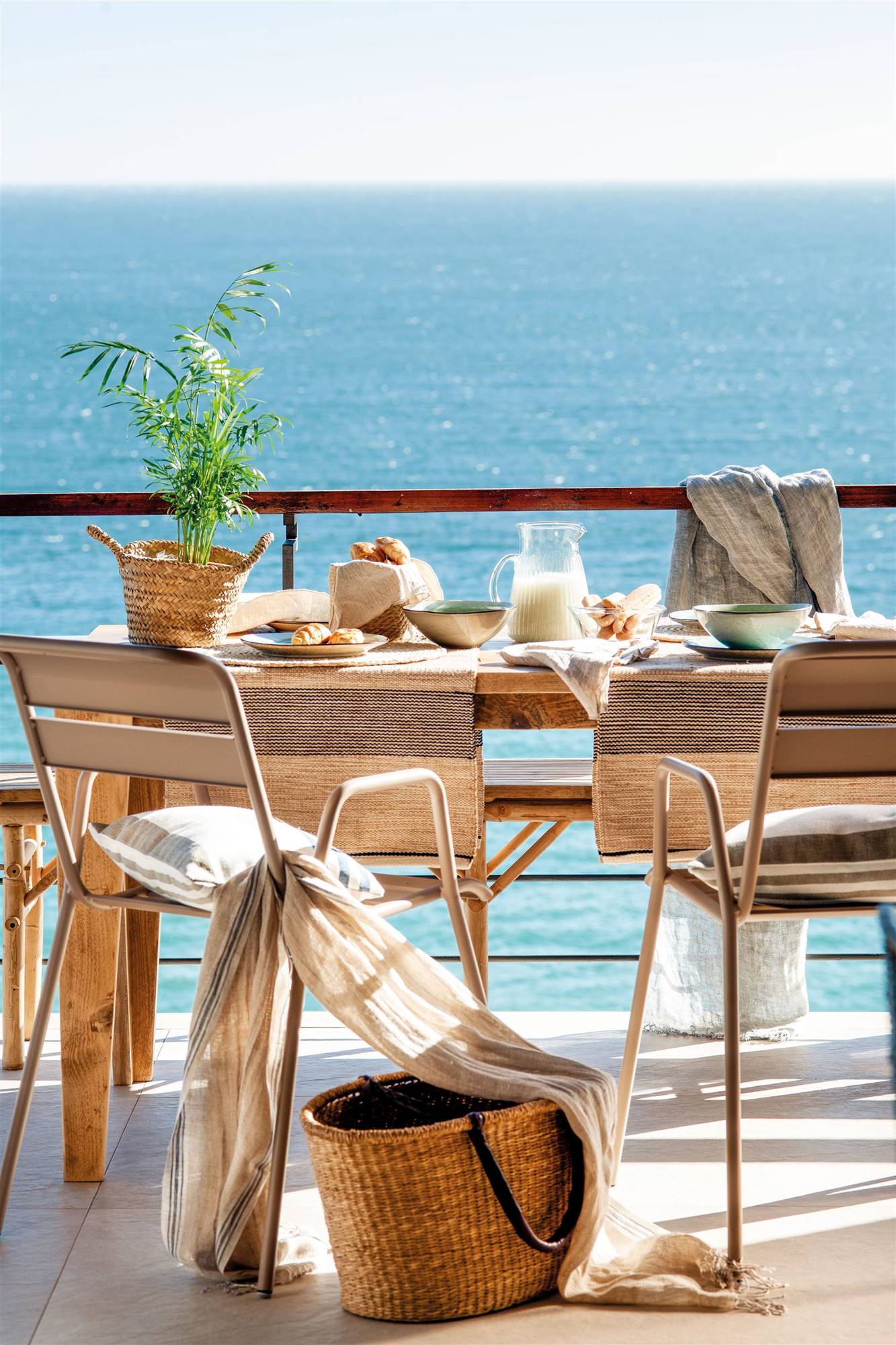 Balcón con comedor exterior con mesa, banco y sillas de madera. 