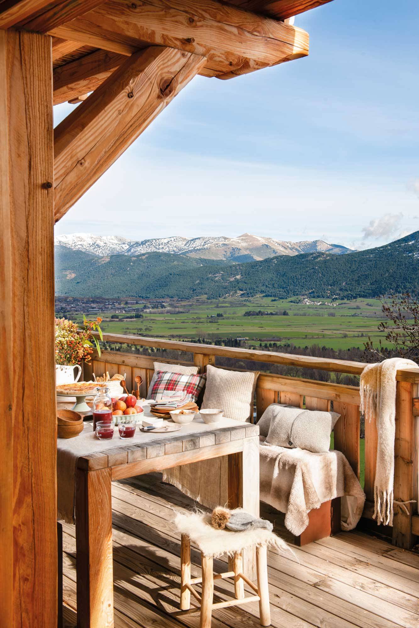 Terraza de invierno con comedor exterior con mesa de madera y bancos. 
