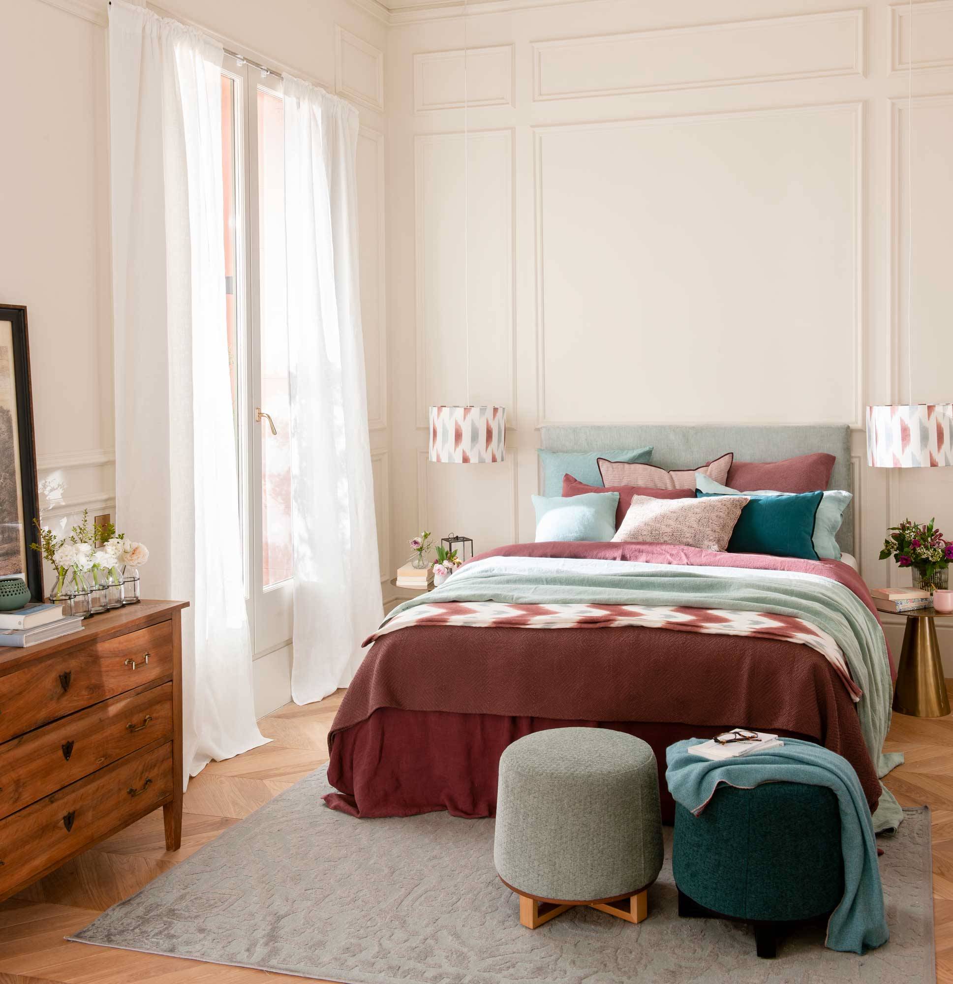 Un dormitorio estilo clásico con colores azul claro y rojo vino, con cabecero mullido. 