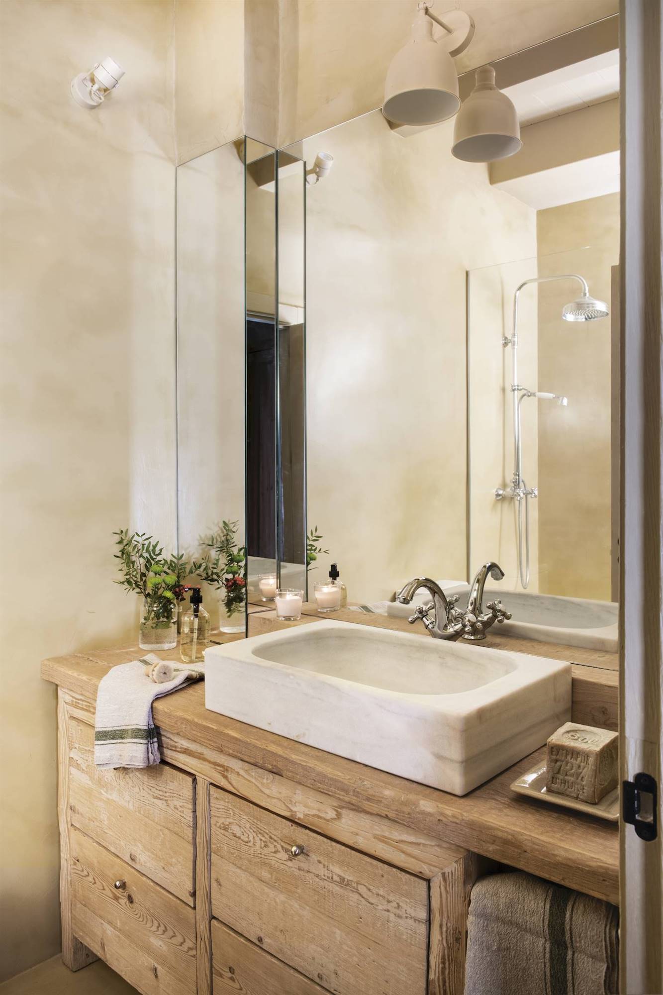 Baño con espejo de lado a lado y mueble para el lavamanos de madera.