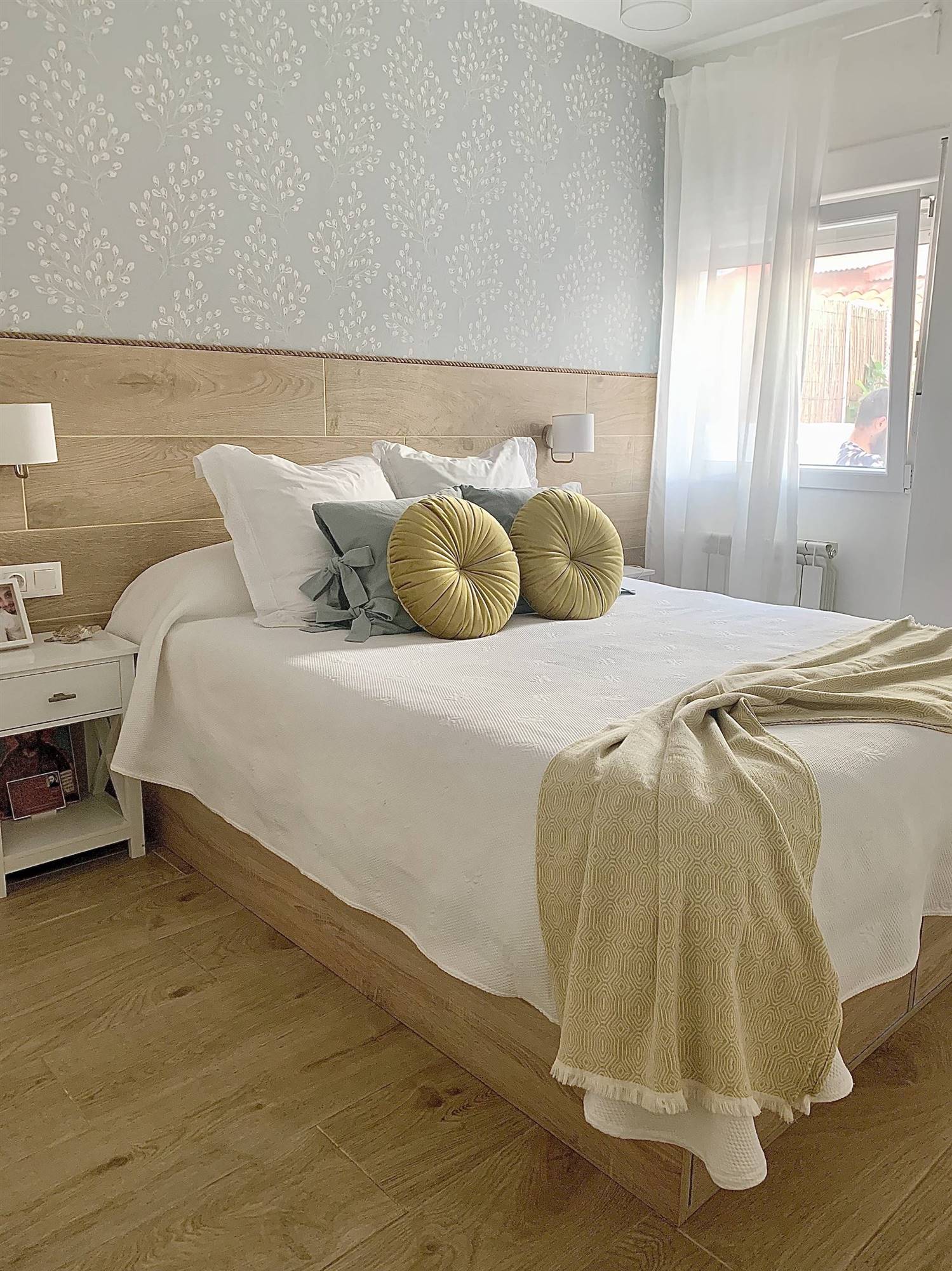 Dormitorio moderno y actual con cabecero de madera y papel pintado con motivos florales.