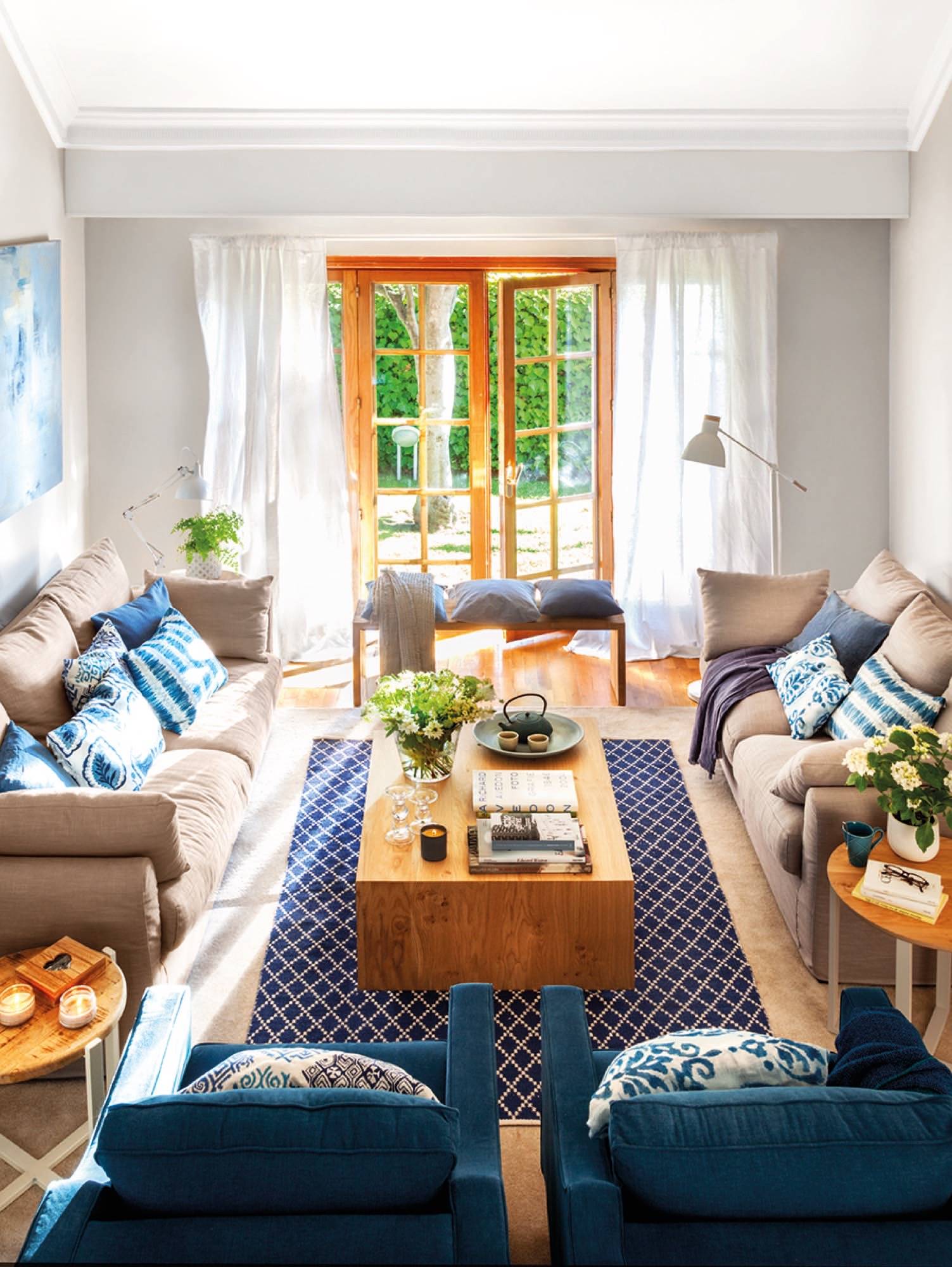 Salón con dos sofás de color beis enfrentados, mesa de madera y textiles azules.
